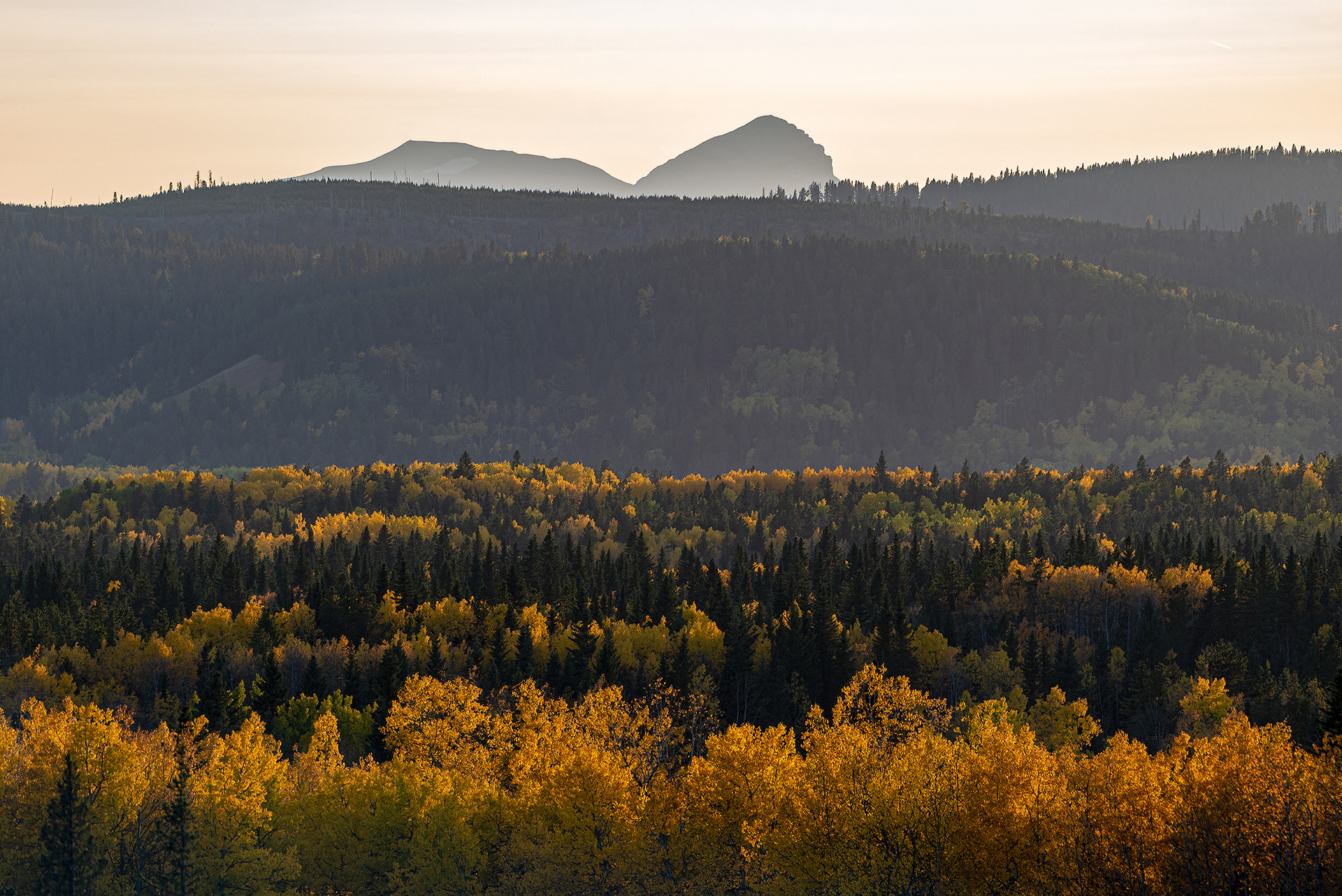Foothills and mountains in a somewhat smoky haze at sunset in Foothills County