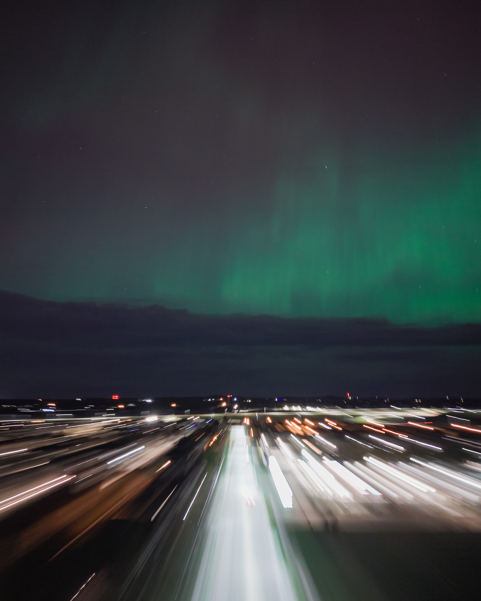 Photo of an Aurora occurrence, with motion blurred neighborhood city lights in the foreground, from Bridlewood, Calgary, AB - May 11th
