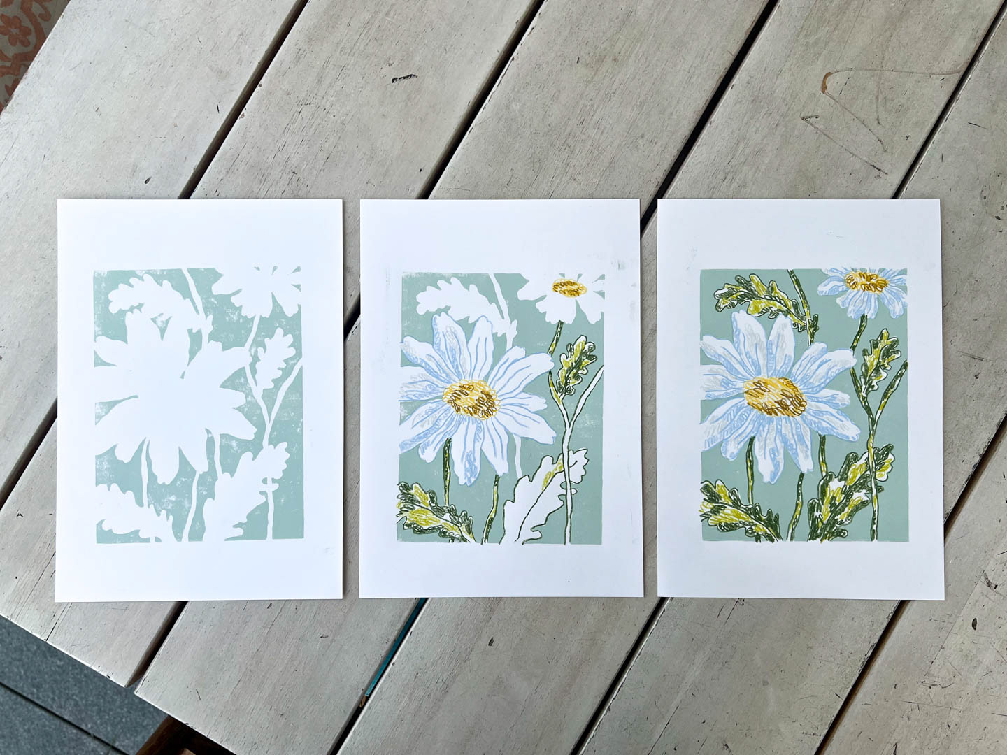 photo of hand-made daisies art prints showing the process with lino cut and coloured pencils. By Bianca Gschlecht