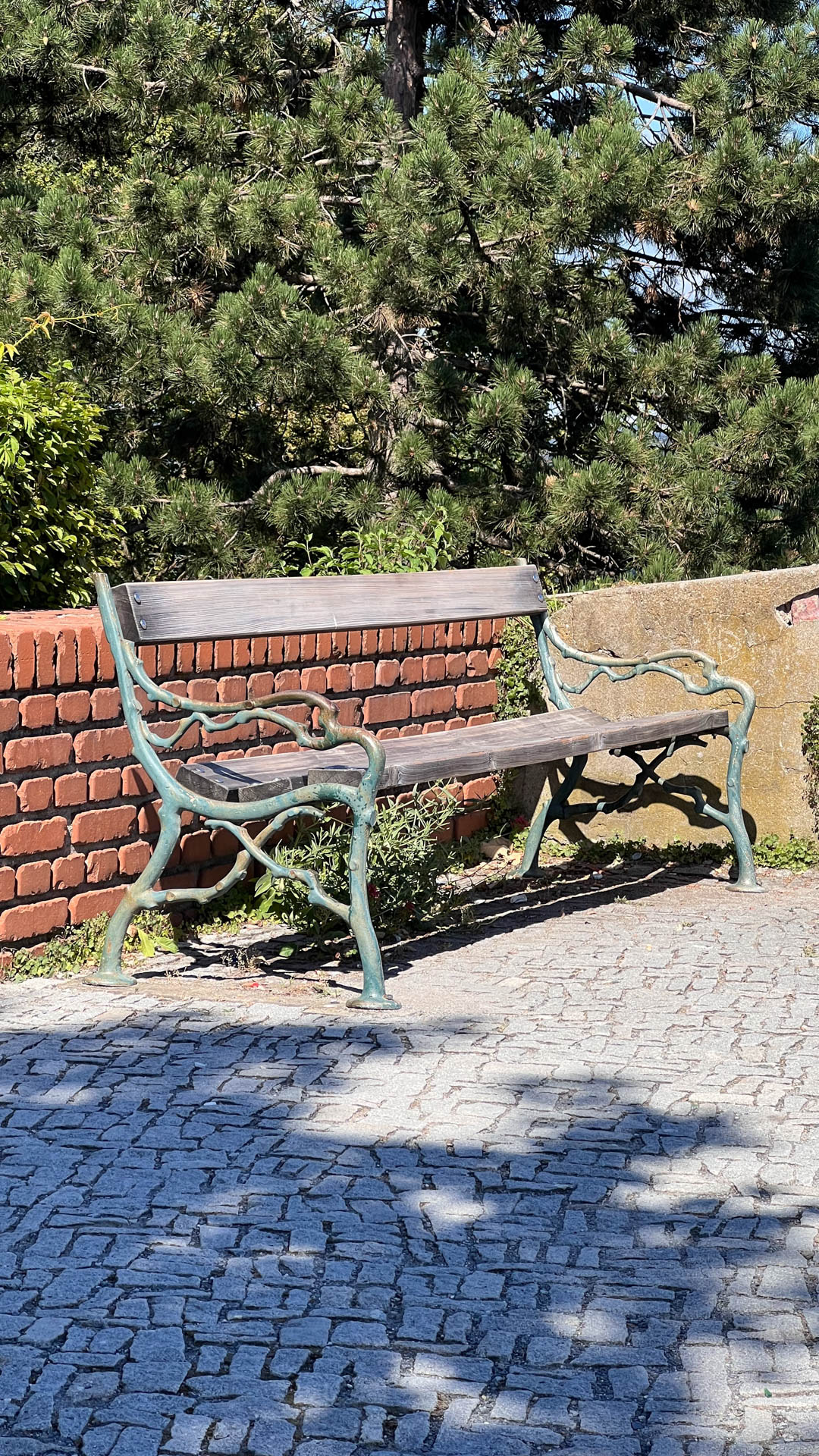 photo of a vintage bench at Schlossberg Graz with brick wall and trees in the back