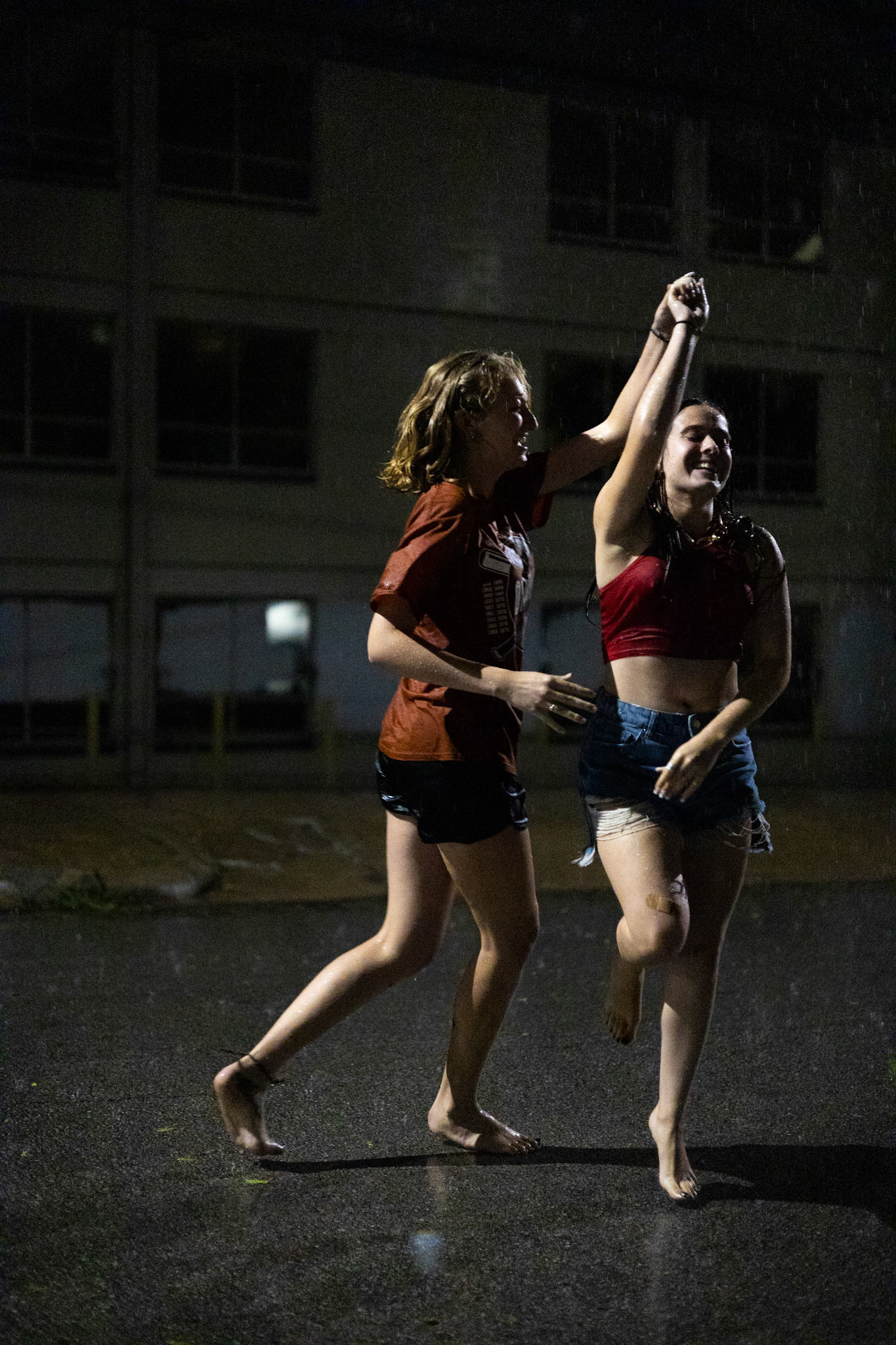 Friends Madi Clayton (left) and Ali Washburn dance in the rain on Leon Street in Austin, TX on September 7th, 2022