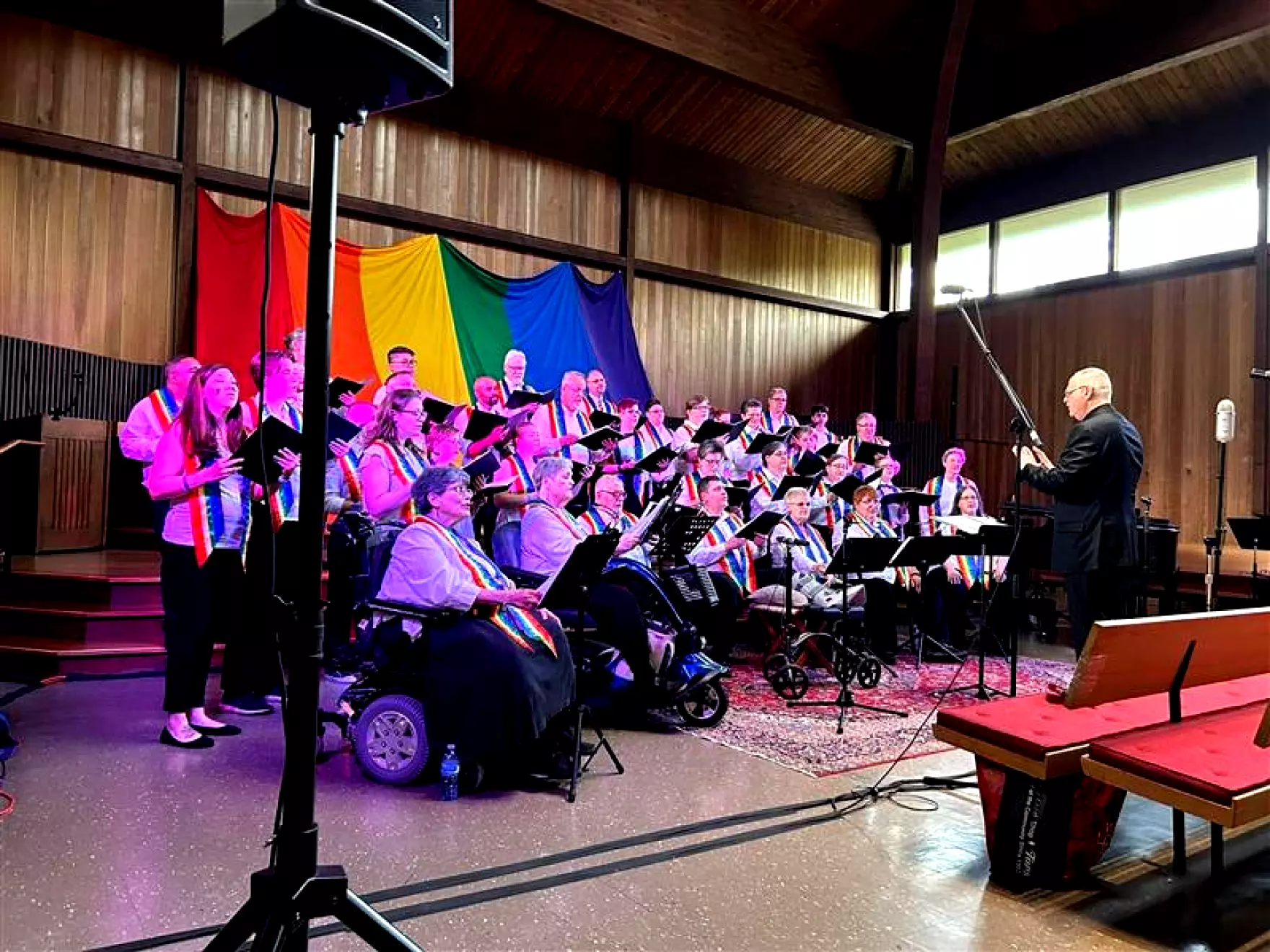 Chorus practicing in front of a pride flag