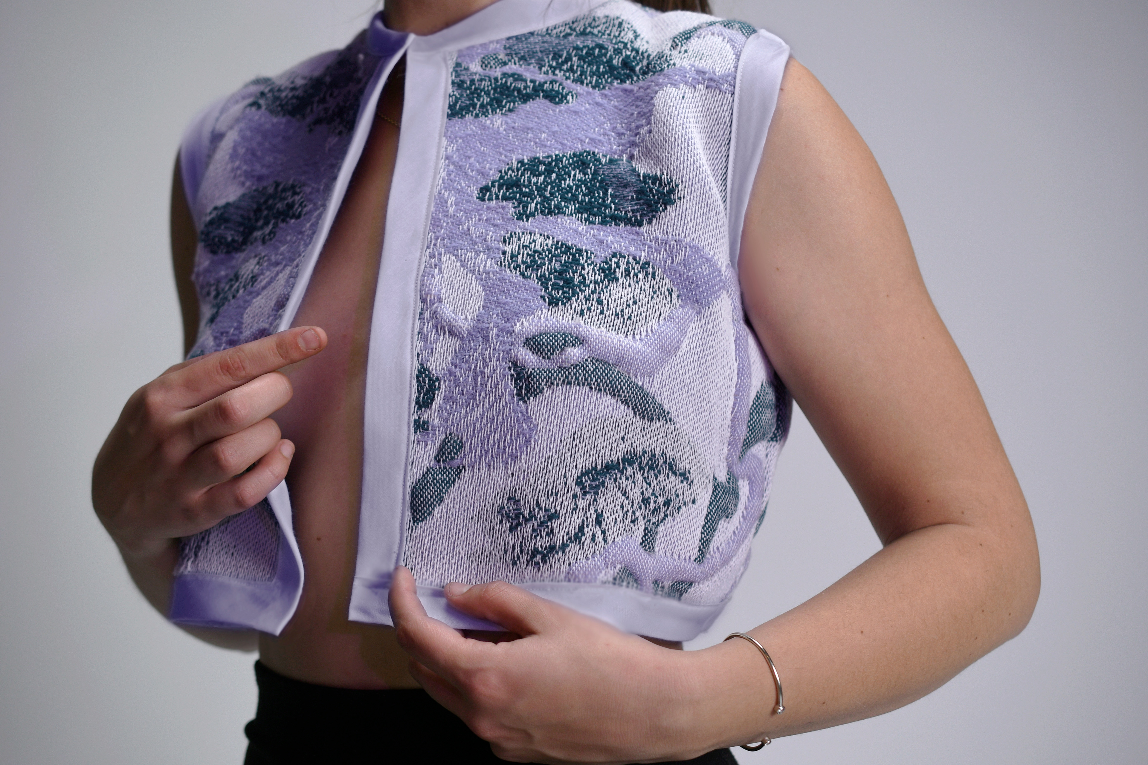 (AVANT) Motif placé sur métier à tisser Jacquard, avec poches rembourées. Les fils de trames de laine ont été teints avant le tissage.