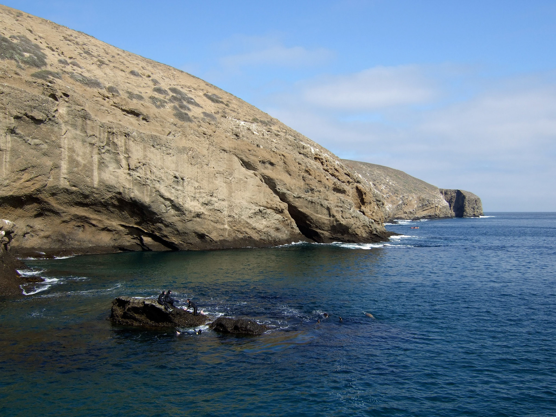 A group of students playing on the rock near the dock and getting pummeled by waves