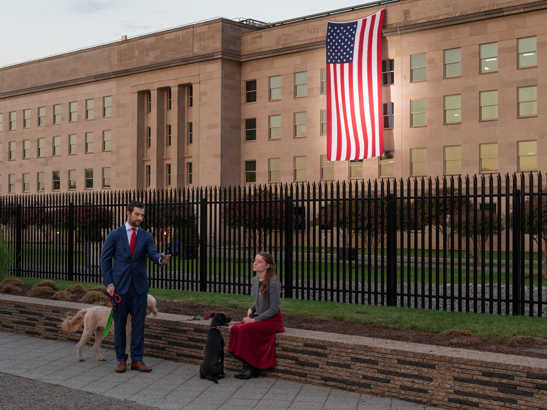 Two visitors dressed in blue and red take their dogs through the 9/11 Pentagon Memorial on the 24th anniversary of the September 11, 2001 terrorist attacks.