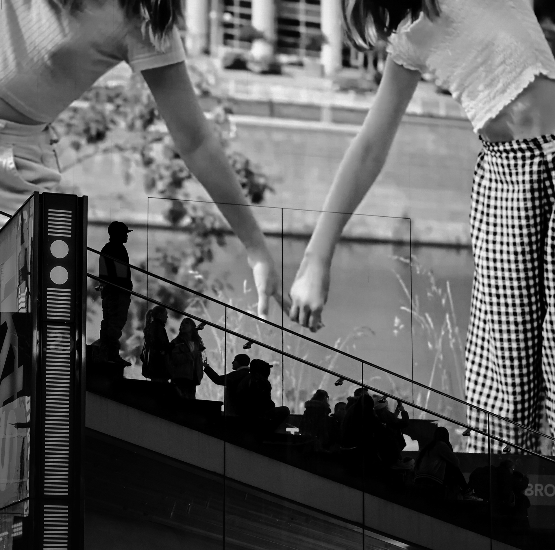 Those standing on the steps in Times Square are silhouetted against a billboard.