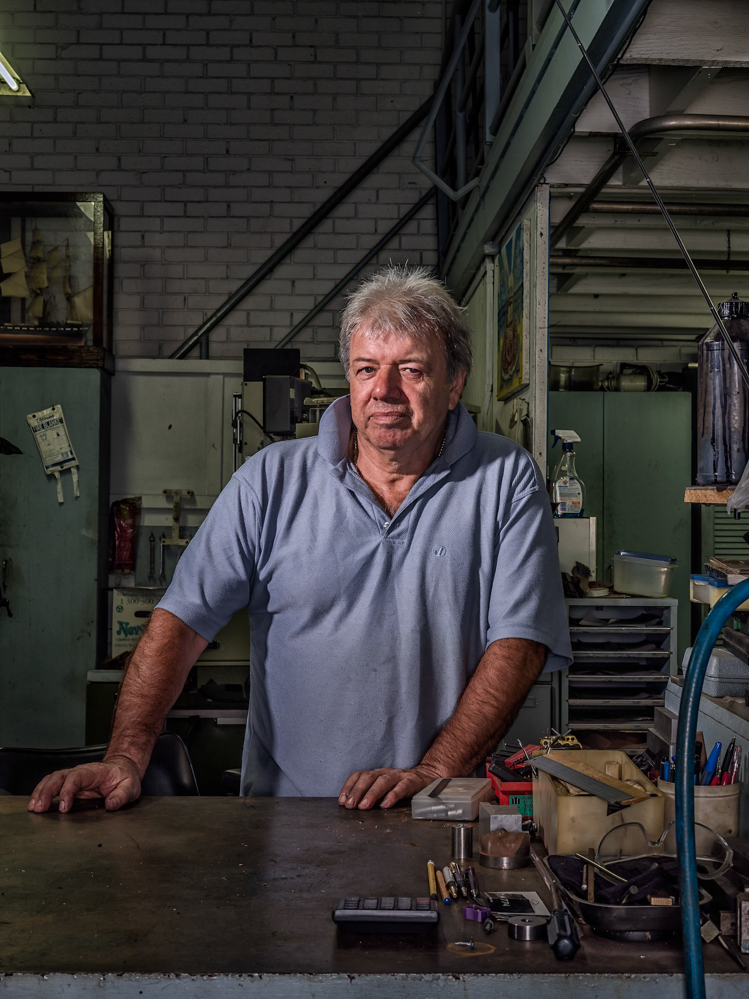 George poses here in his workshop in Milperra, it is filled with a vast array of machinery and tools to work with metal, he used to be very busy. These days much of the work that he used to do has been outsourced to overseas manufacturers for prices he cannot compete with. Now with only the odd job to keep him going, his workshop is slowly transforming around him into a museum.