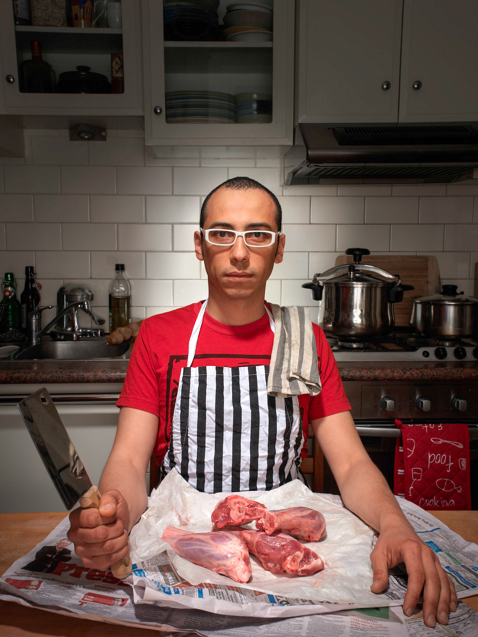This photo was taken about three years ago in Tawf’s kitchen, it came about as a collaboration between us as part of a personal project that I have been working on for a while now. The idea plays on a few things that are connected to Tawf, his love of food and his cultural background. Tawf’s full name is Tawfic Elgazzar, his last name translated into english means butcher which is the nickname that he goes by. The choice of lamb shanks is a reference to his Arabic background, Tawf is from Egypt, the sphinx like pose is actually a coincidence, it worked for the shot and we went with that.The colours were deliberately kept subdued in the background to bring focus to the red colours, linking the lamb with his shirt and stove in the background; creating the link to culture, the person, and cooking.You’ll notice the pressure cooker on the stove, well after the shoot Tawf put those lamb shanks into the cooker and we ate them, the meat was still fresh.