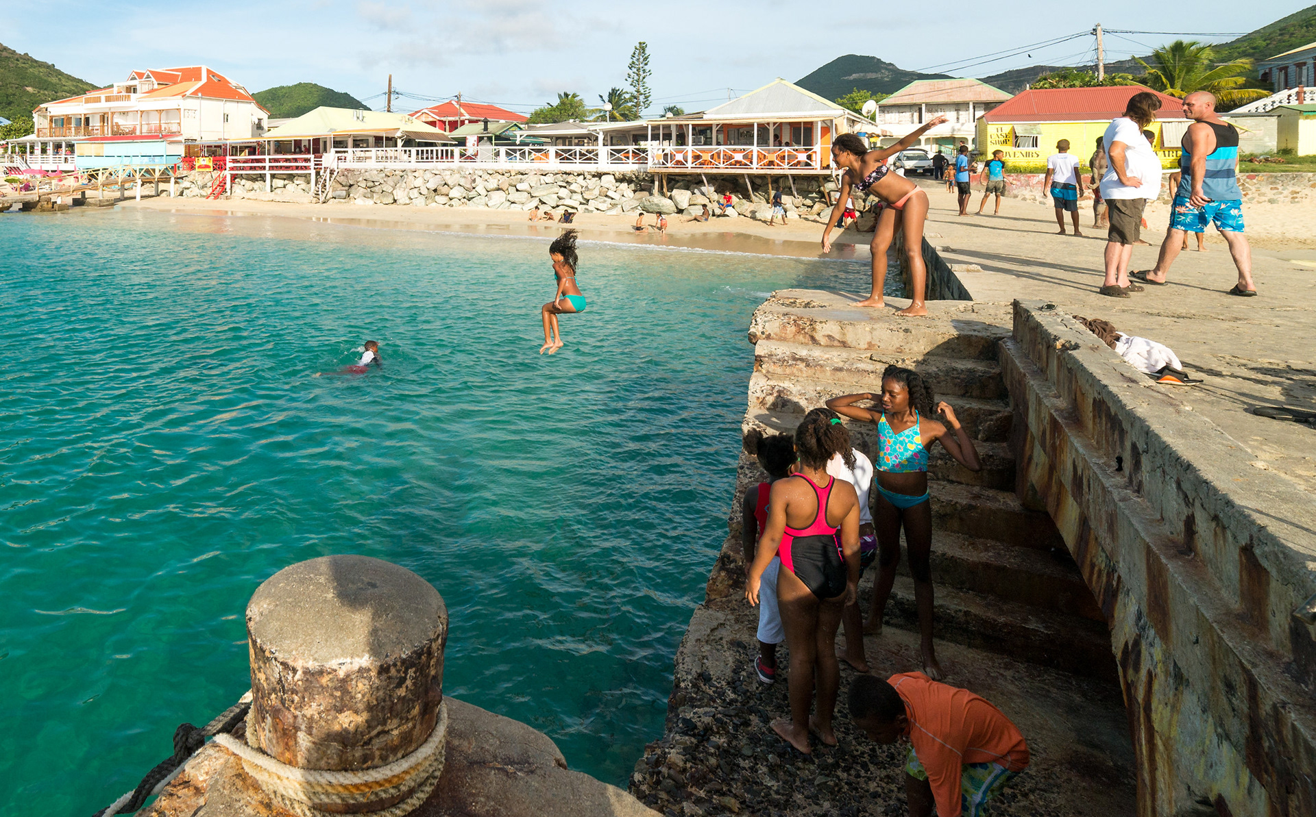 SUMMER TIME!! - Kids playing and enjoying the hot summer day, over an old pier at Grand Case beach, Saint Martin.