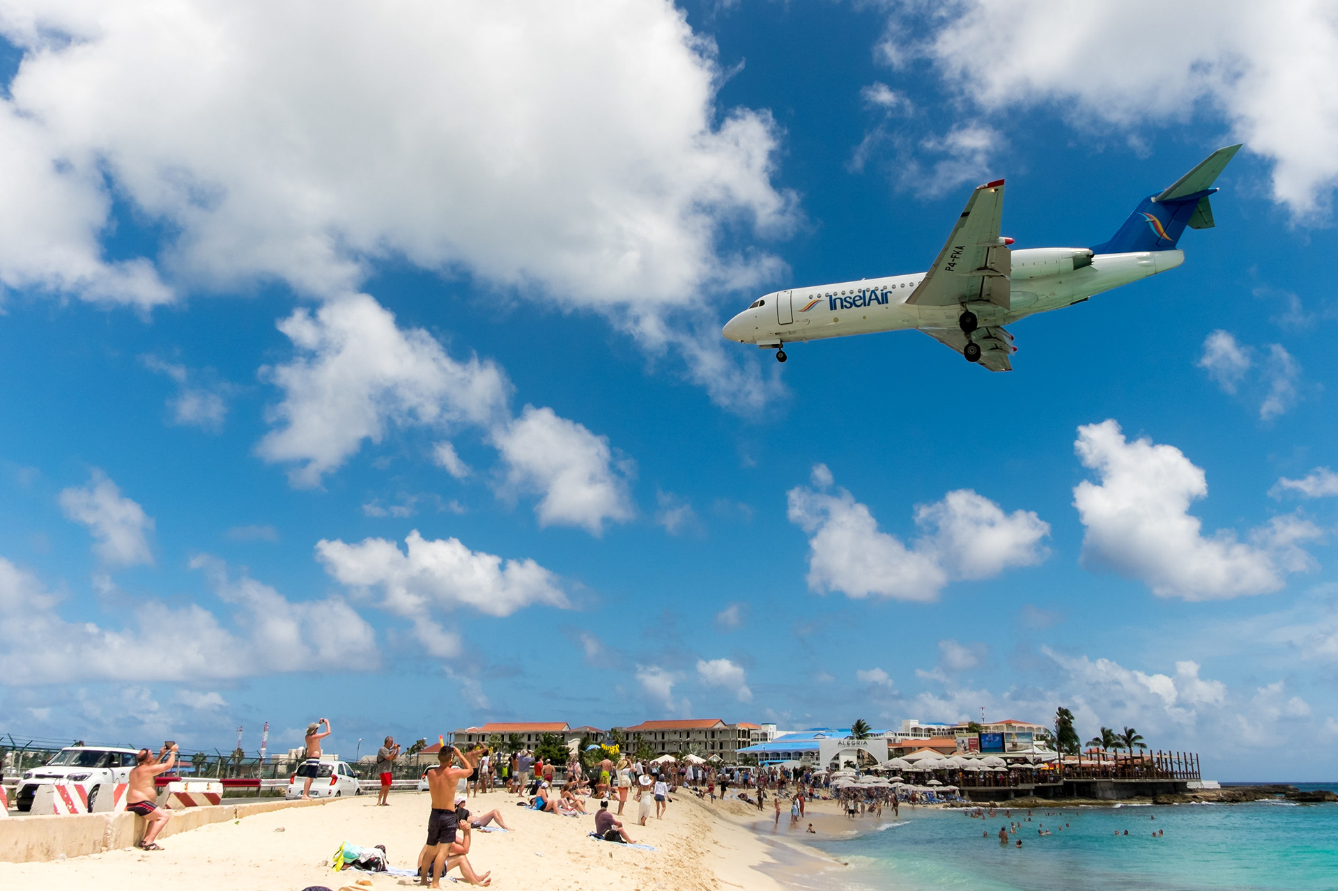 GOING DOWN - A big plane is landing at Princess Juliana International Airport next to a pretty crowded Maho Beach. Saint Martin.