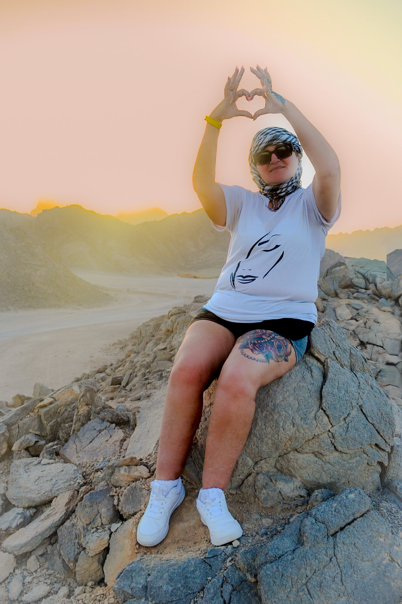 Lady at sunset in the desert making a love heart with her hands