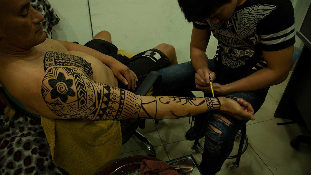 Dalit (Shane Rangi) gets his tattoos applied by Yuri Mejal