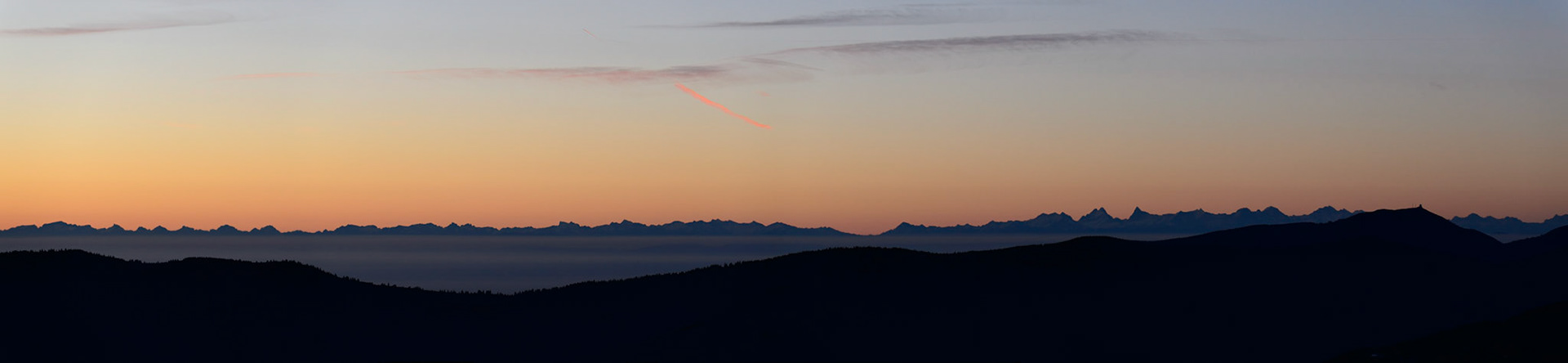 Scenic view from the Vosges mountains in France towards the Swiss alps during sunrise, with the high peaks of Jungfrau, Eiger and Matterhorn.