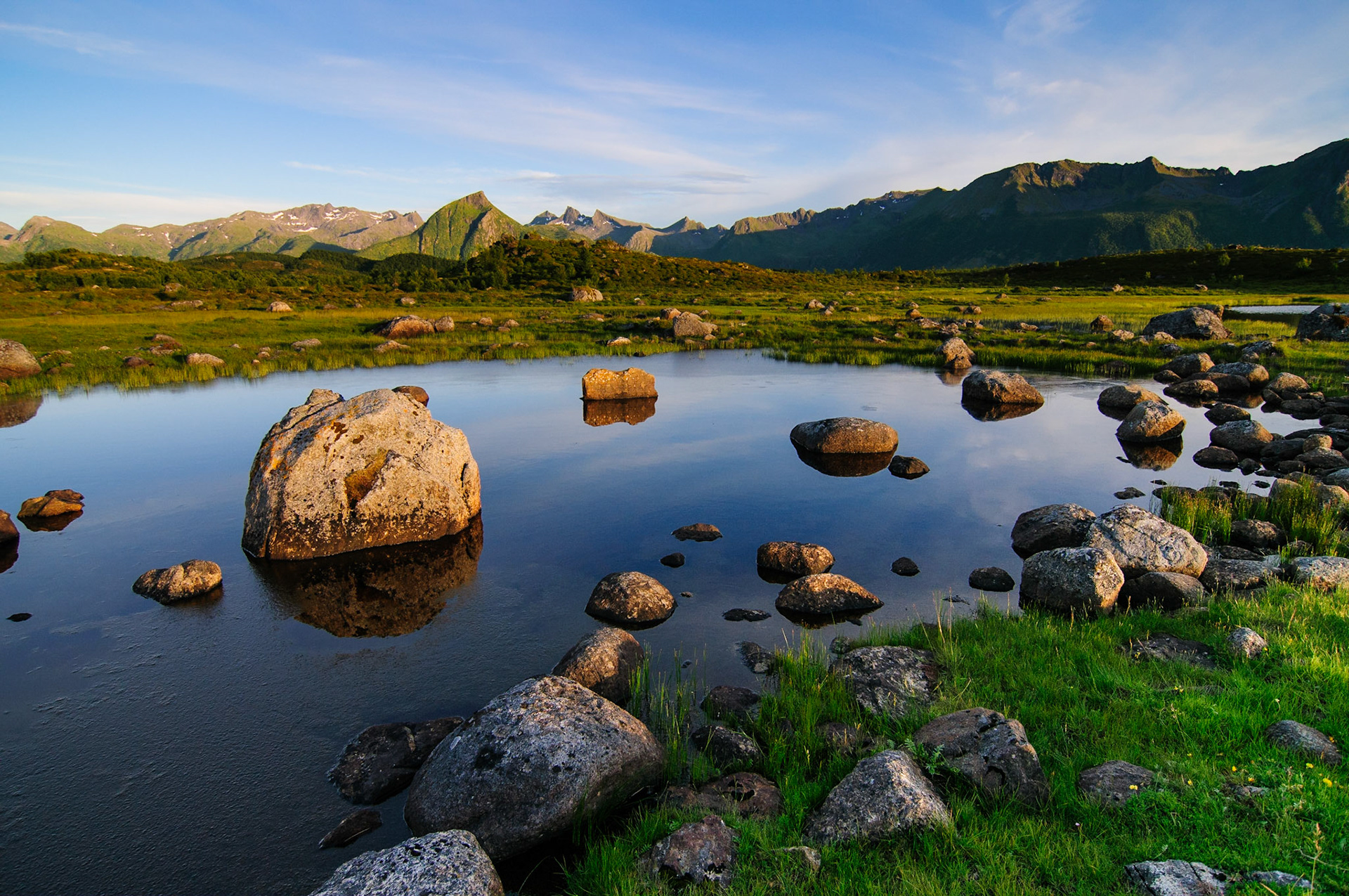 The mountains of the Lofoten islands reflect in a lake in beautiful evening light