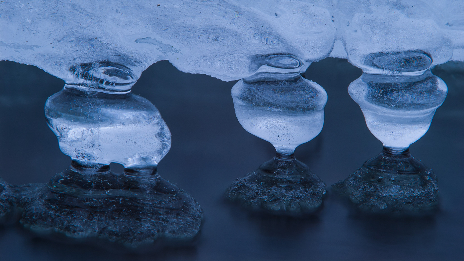Een kabbelend bergbeekje stroomt onder het ijs. Het golvende water vormt kunstige ijsdruppels.