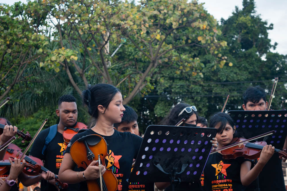Jóvenes músicos tocando violines en espacio público de Siloé, Cali, fotografía documental comunitaria y cultural.