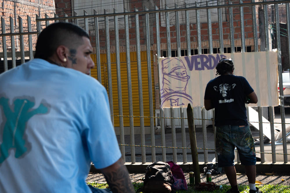 Grafiti urbano en Siloé, Cali, con artistas callejeros pintando mural sobre verdad y memoria, fotografía documental de arte urbano y contexto social.