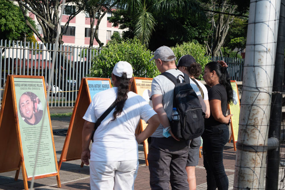 Personas leyendo exposición comunitaria en espacio público de Siloé, Cali, fotografía documental social y urbana.