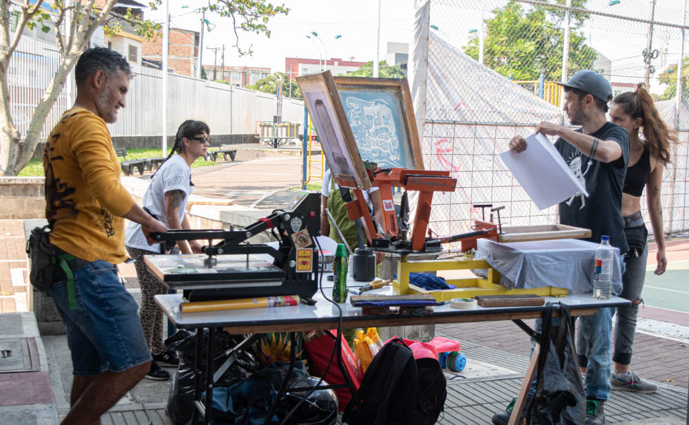 Jornada de serigrafía comunitaria en espacio público de Siloé, Cali, producción gráfica colectiva, fotografía documental.