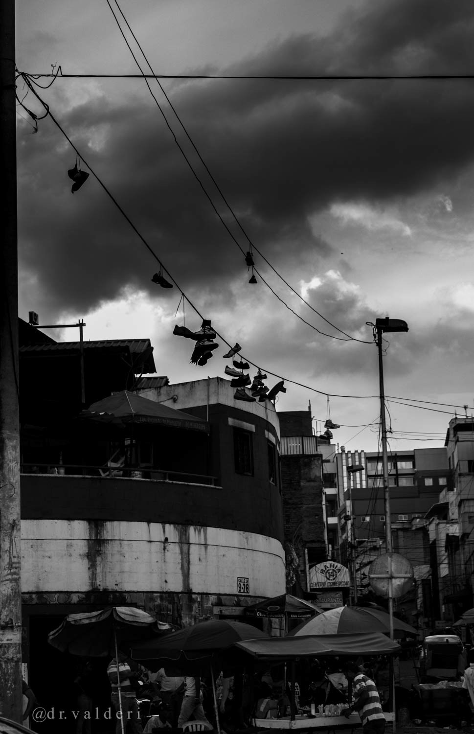 Zapatos colgados en cables eléctricos en Siloé, Cali, Colombia, como símbolo urbano del territorio, registrados mediante fotografía documental en blanco y negro.
