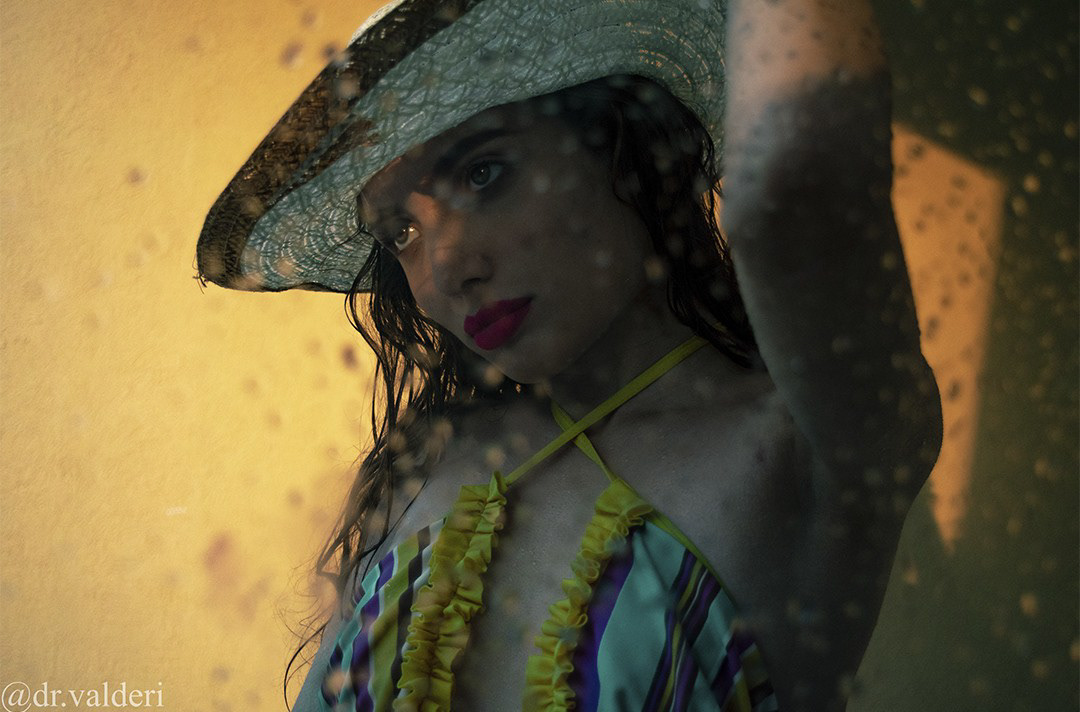 Fotografía artística contemporánea de mujer con sombrero y luz dramática.