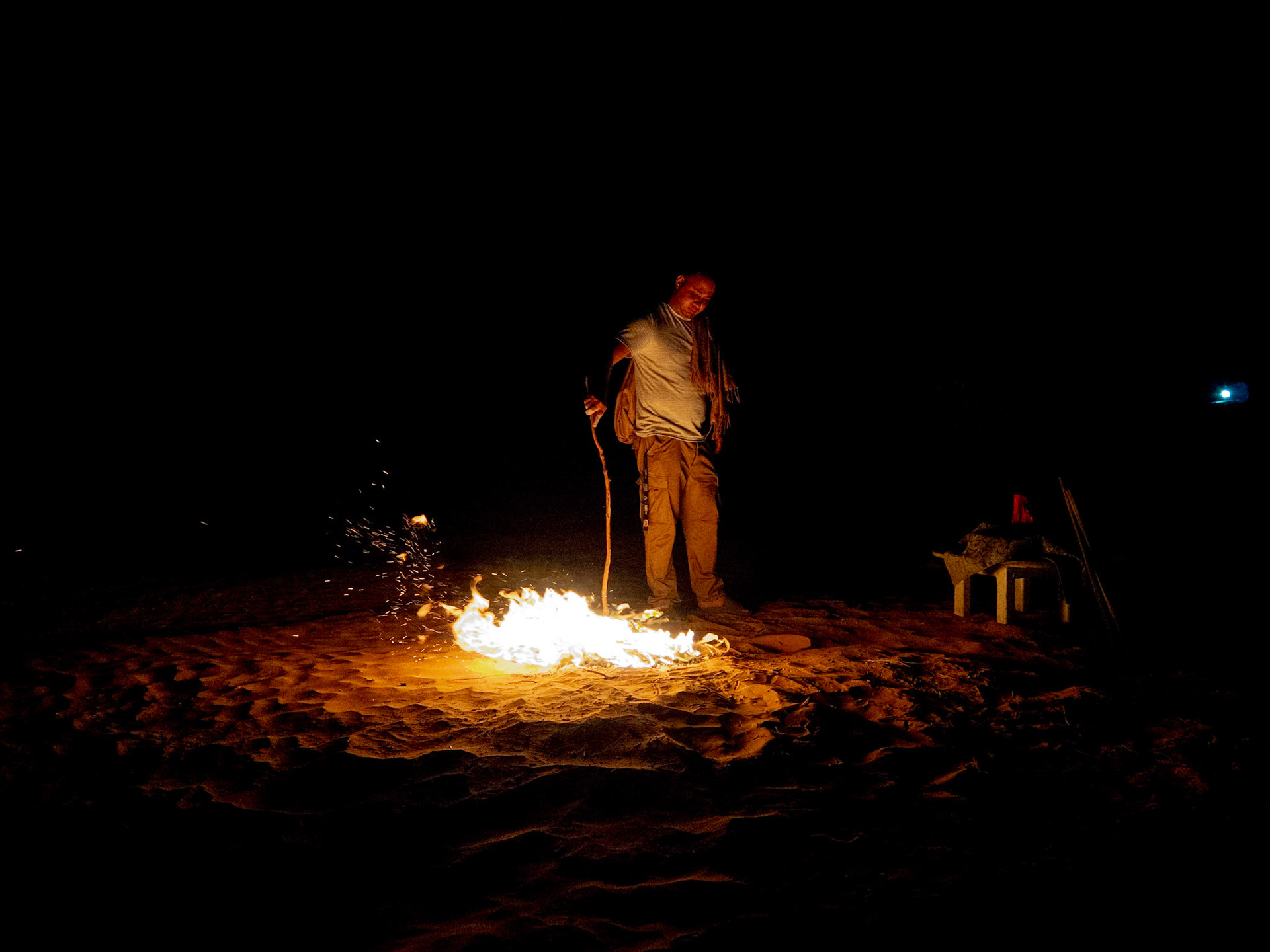 Hassan, guide touristique, alimente un feu de camp afin de cuire un pain de sable, au campement Zmela Labrissa. Il affirme se faire un pain de sable à tous les jours.