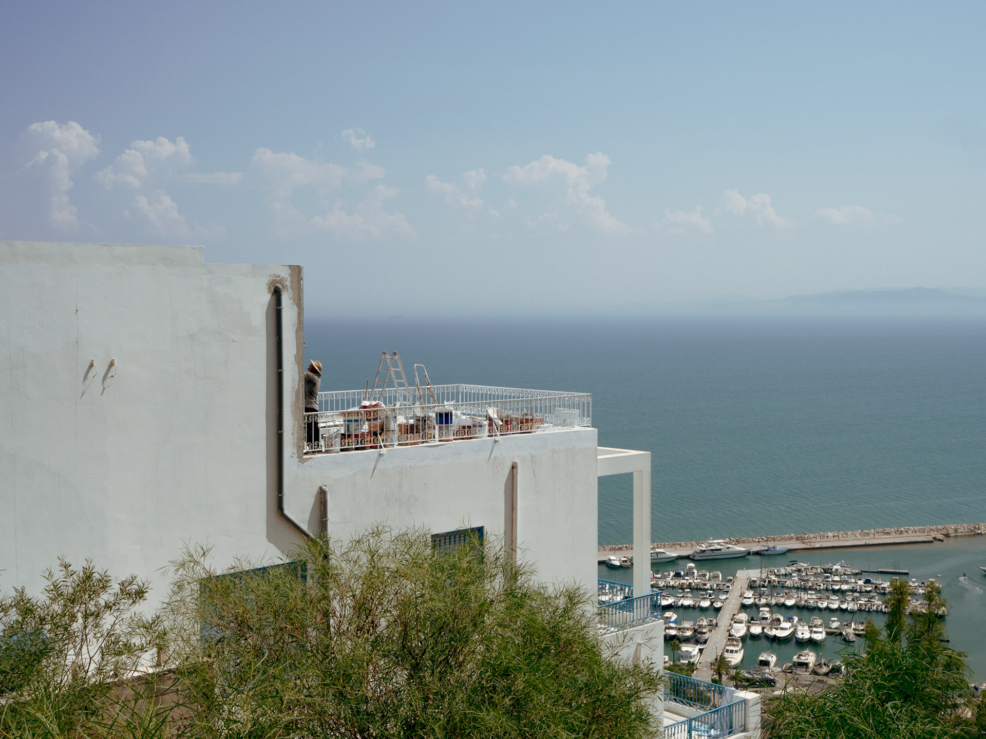 Un travailleur sur une galerie à Sidi Bou Saïd avec vue sur le Golfe de Tunis