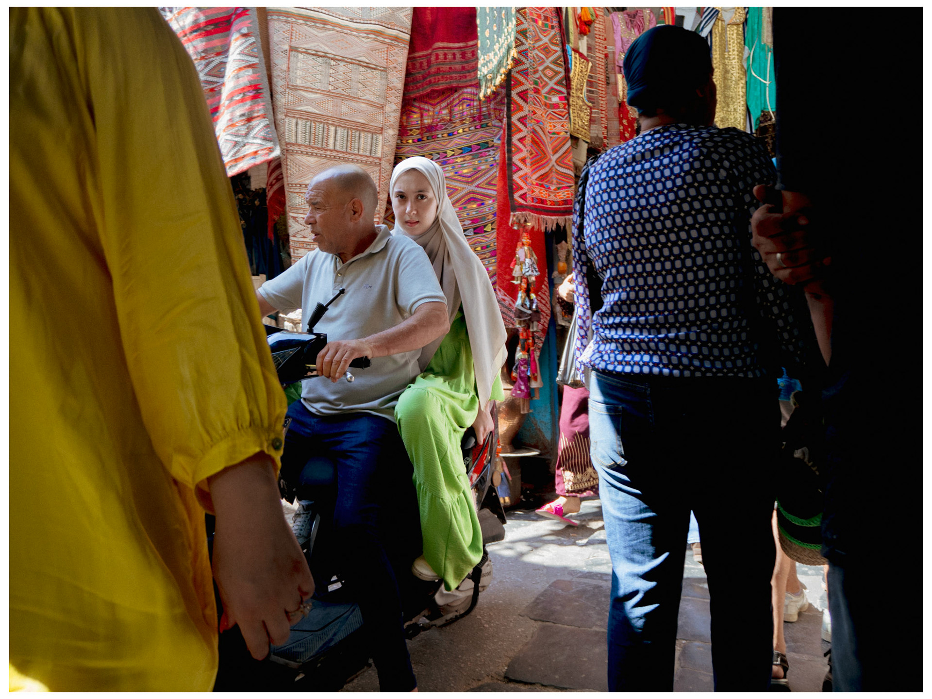 Une jeune femme en motocyvlette observe les passants dans la Souk
