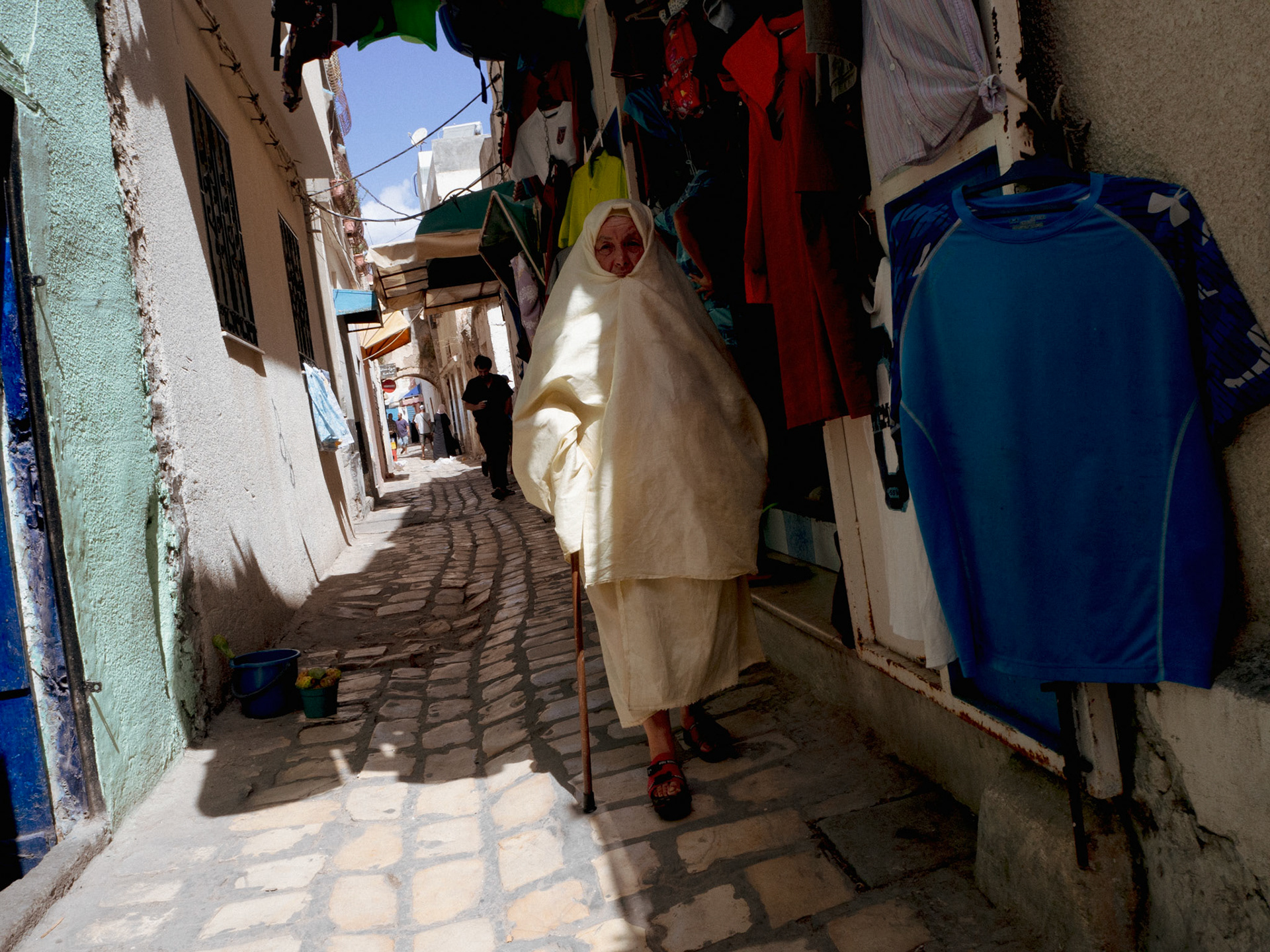 Une habitante de Bizerte arpente les rues de la médina en direction du marché, où on y trouve de nombreuses brocantes et friperies.