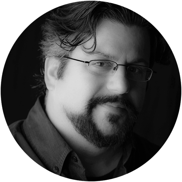circle photo in black and white of man with glasses and facial hair on black background