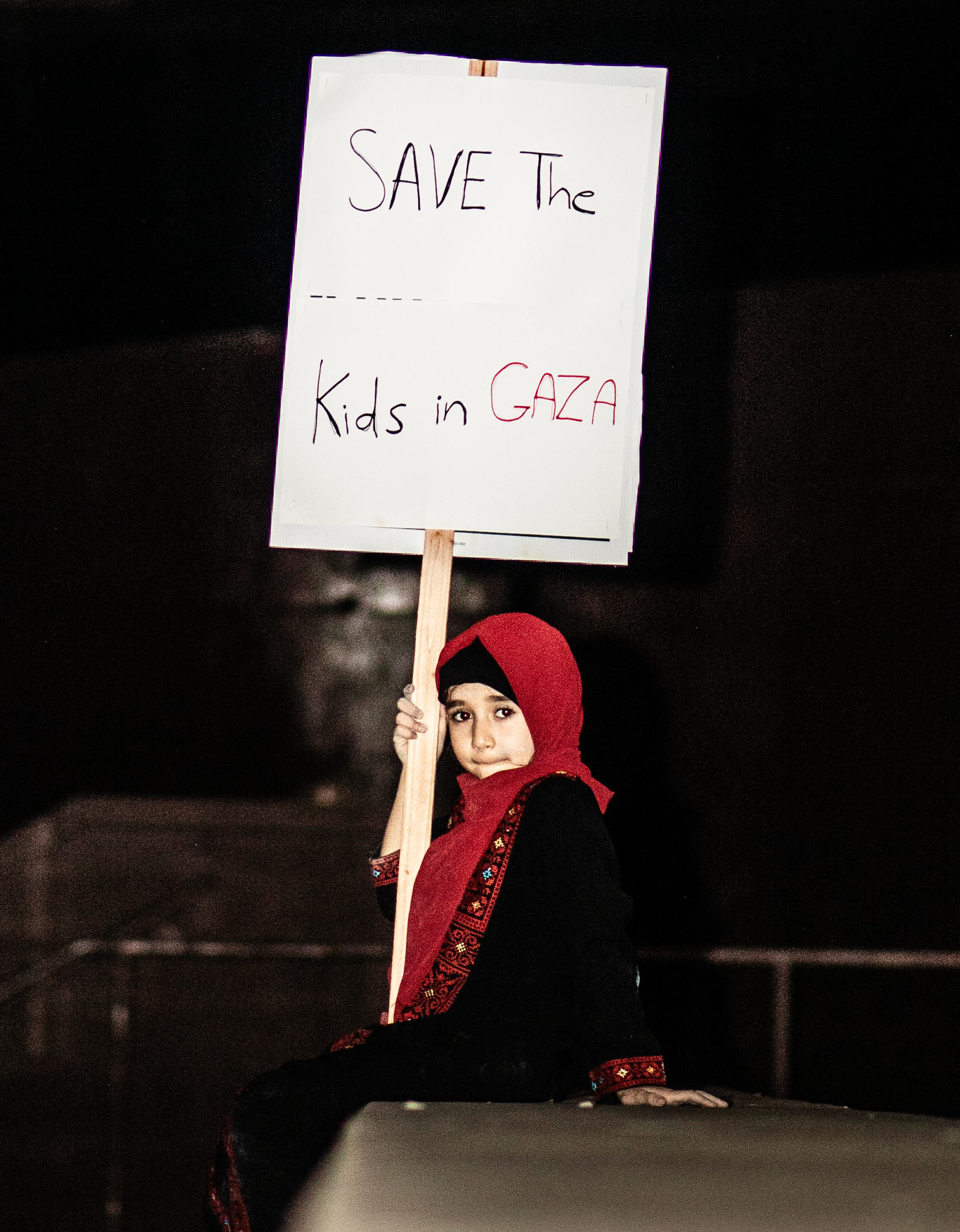 7-year-old Mariam Mohd holds up a sign reading “Save the kids in Gaza” at the vigil for the 4100 and more children of Gaza who have been killed.
