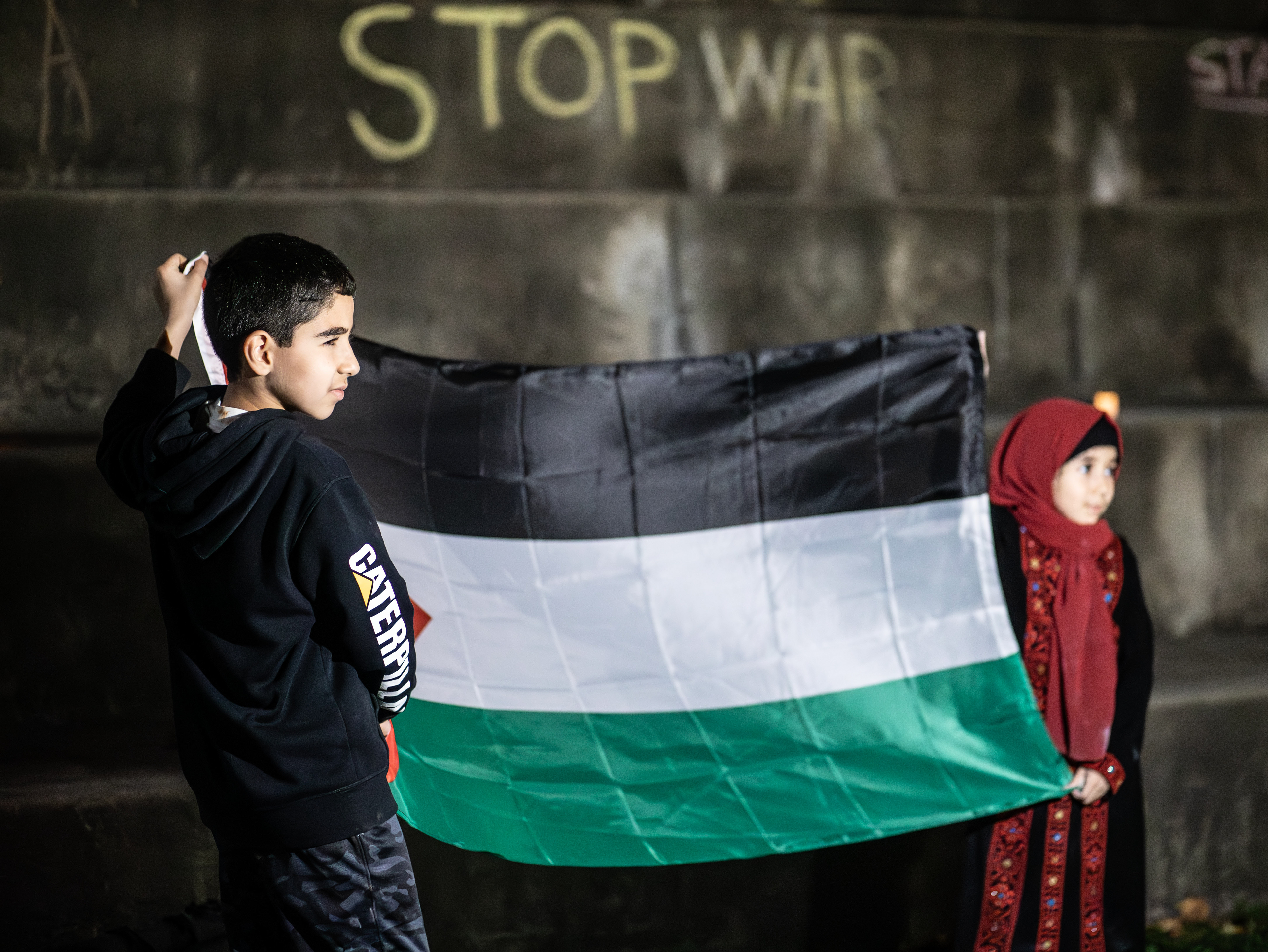 9-year-old Mohammad Mohd and his 7-year-old sister Mariam Mohd raise up a Palestinian flag at the vigil for Gaza’s children Wednesday night.