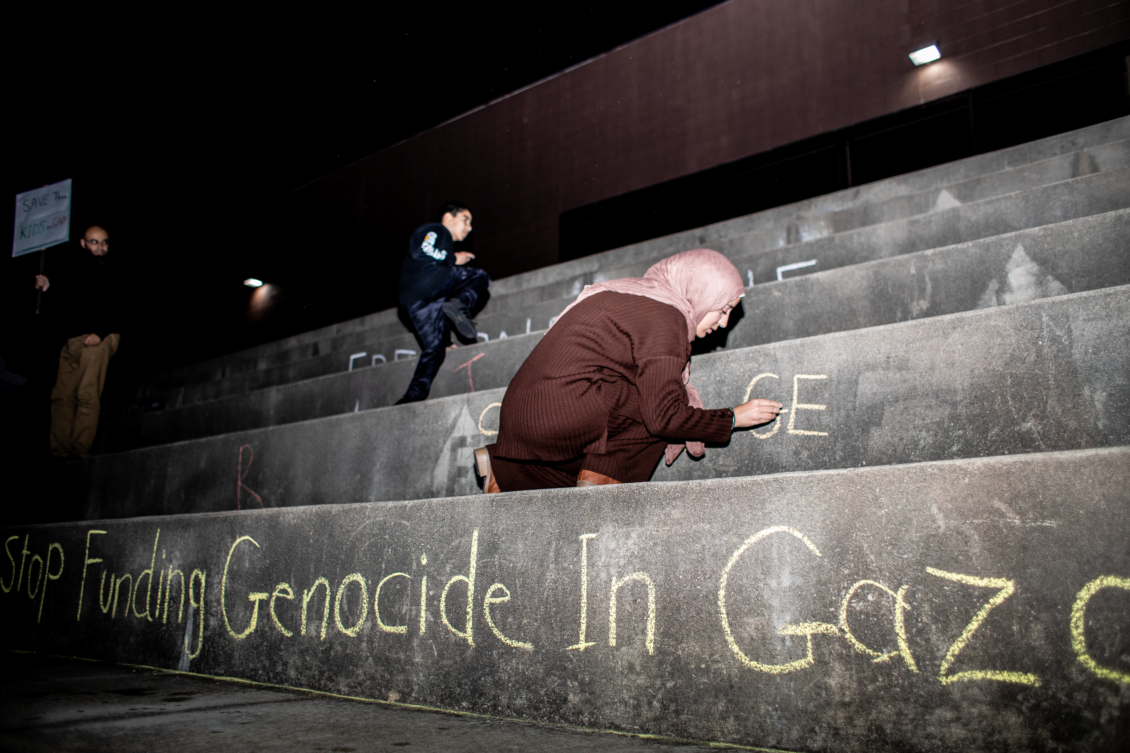 ahani Bilkhair writes “Stop the genocide” on the Mellin steps during a vigil for Gaza’s children.
