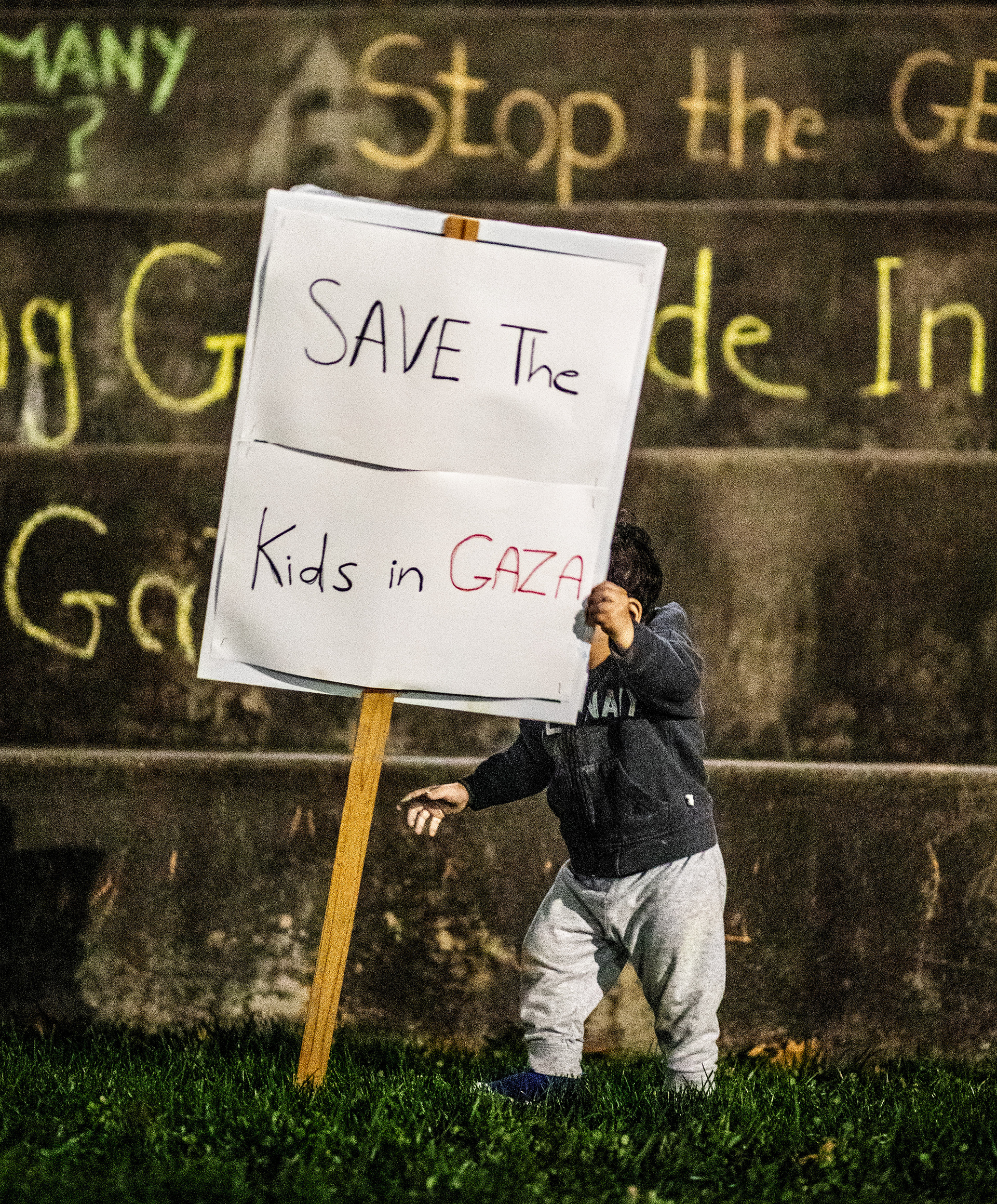 Esraa Jarrar’s child picks up a sign saying, “Save the kids in Gaza” at the vigil for the children in Gaza who have been killed.