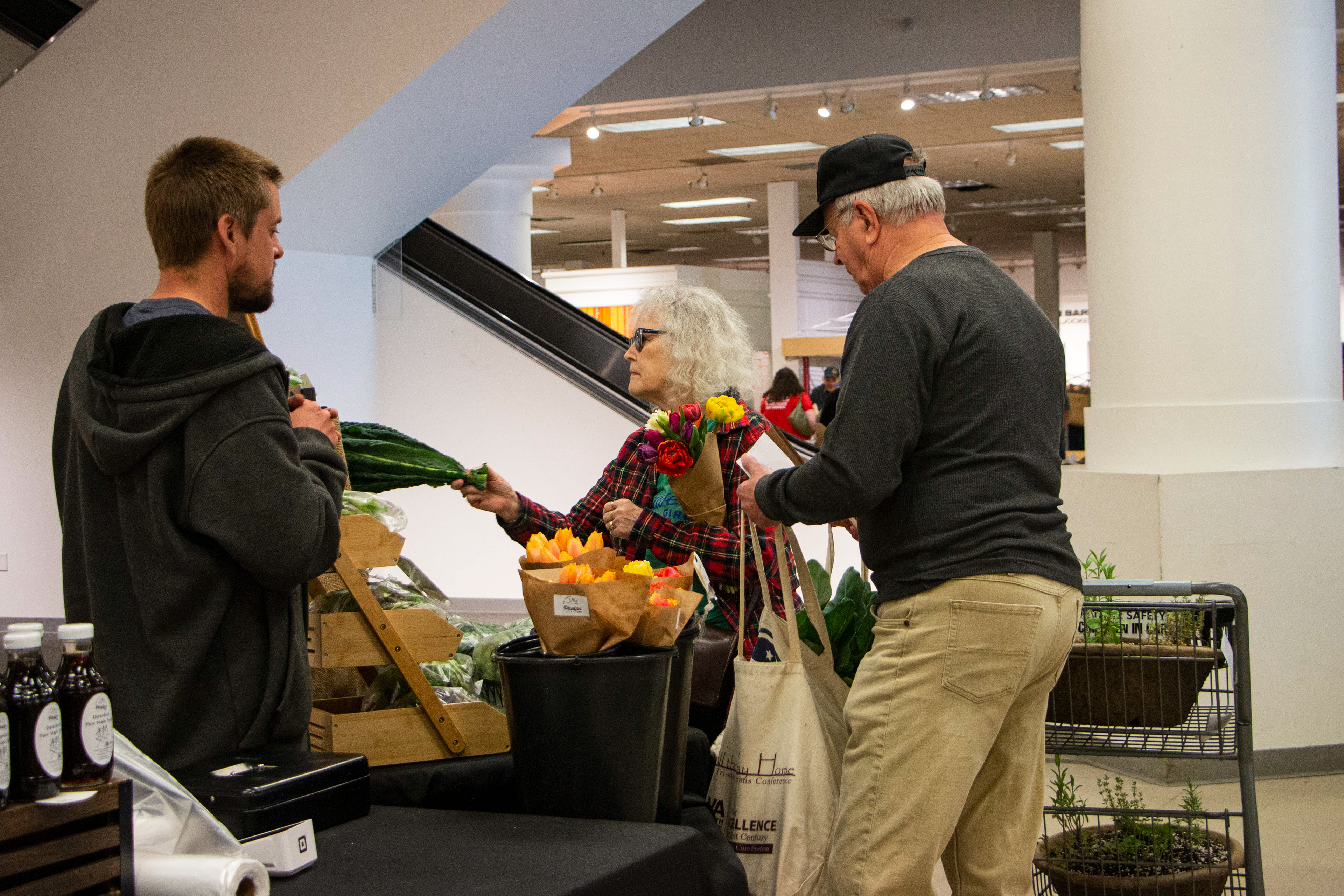 Winter Farmer's Market at Kennedy Mall in Dubuque, IA on April 27, 2024. Andrew Phelps sells some of his organic products to an elderly couple.
