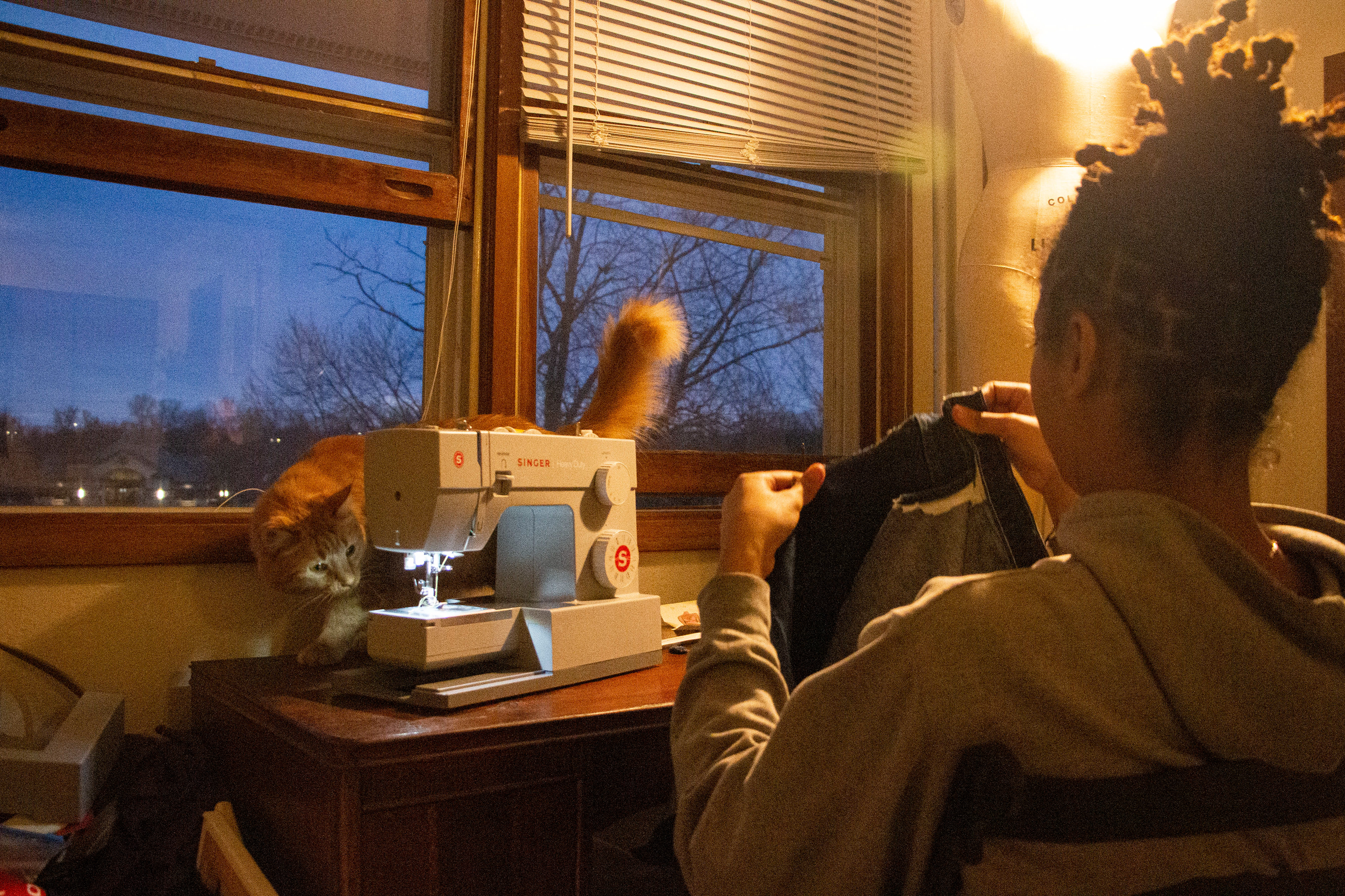 Jahn Hawkins takes the pockets out of thrifted pants to sew them on a top she is working on for a fashion show in Coralville on Thursday, Feb. 15, 2024. Jahns lives with her two cats Buddha aand Kyba.