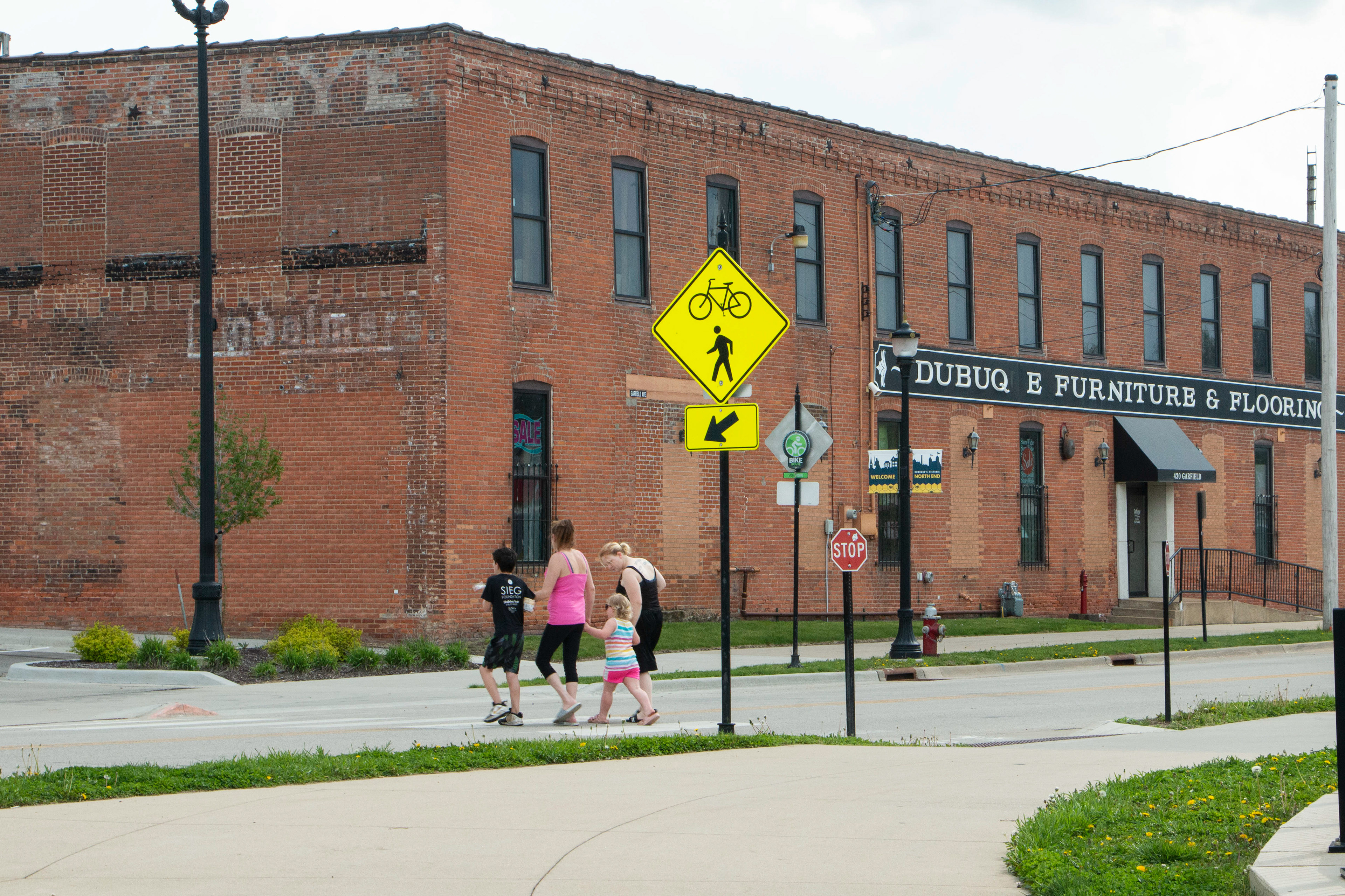 Bee Branch Trail in Dubuque, IA on April 27, 2024. A family uses the cross walk for pedestrians and cyclists that is part of the Bee Branch Trail made by the engineer Steve Sampson Brown who is also involved in creating the Mobility Passion Team working in the bike lane project.