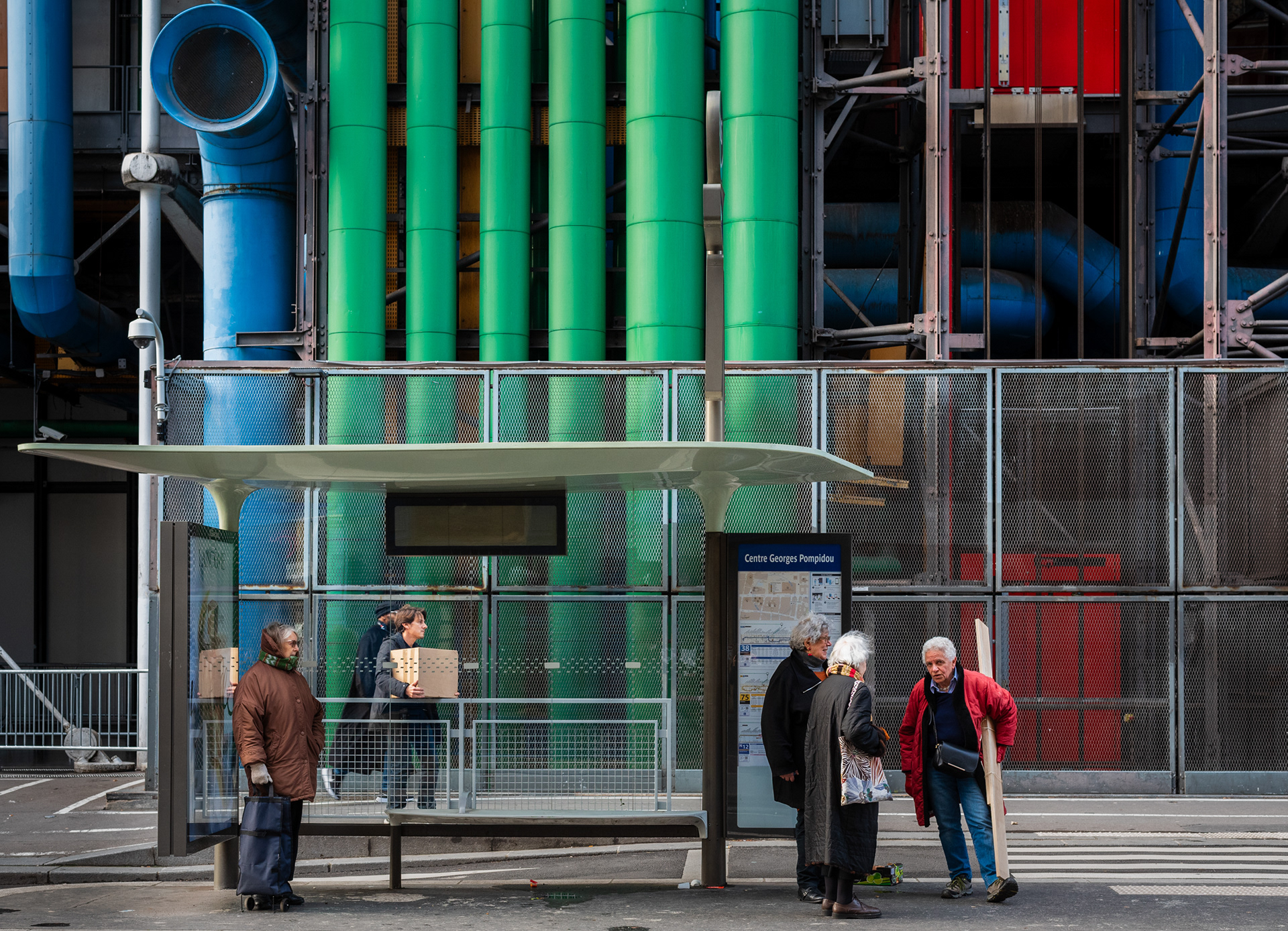 People waiting at the bus stop in front of the Centre Pompidou. The coloured pipes are one of the architectural characteristics of the extraordinary building, which was also called "Notre Dame of the Pipes" by its many critics after its construction in the 1970s. Paris, France, December 8, 2023.