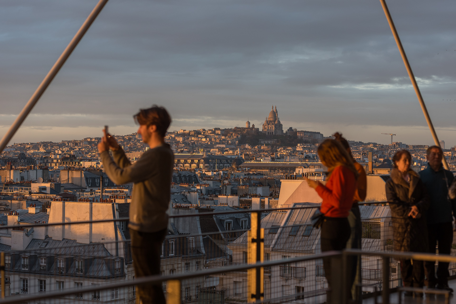 Visitors gather on the Centre Pompidou terrace to watch the sunset and capture pictures. The terrace of the cultural centre provides an excellent panoramic view of Paris rooftops and renowned landmarks like the Sacré-Cœur and Eiffel Tower. Paris, France, December 8, 2023.