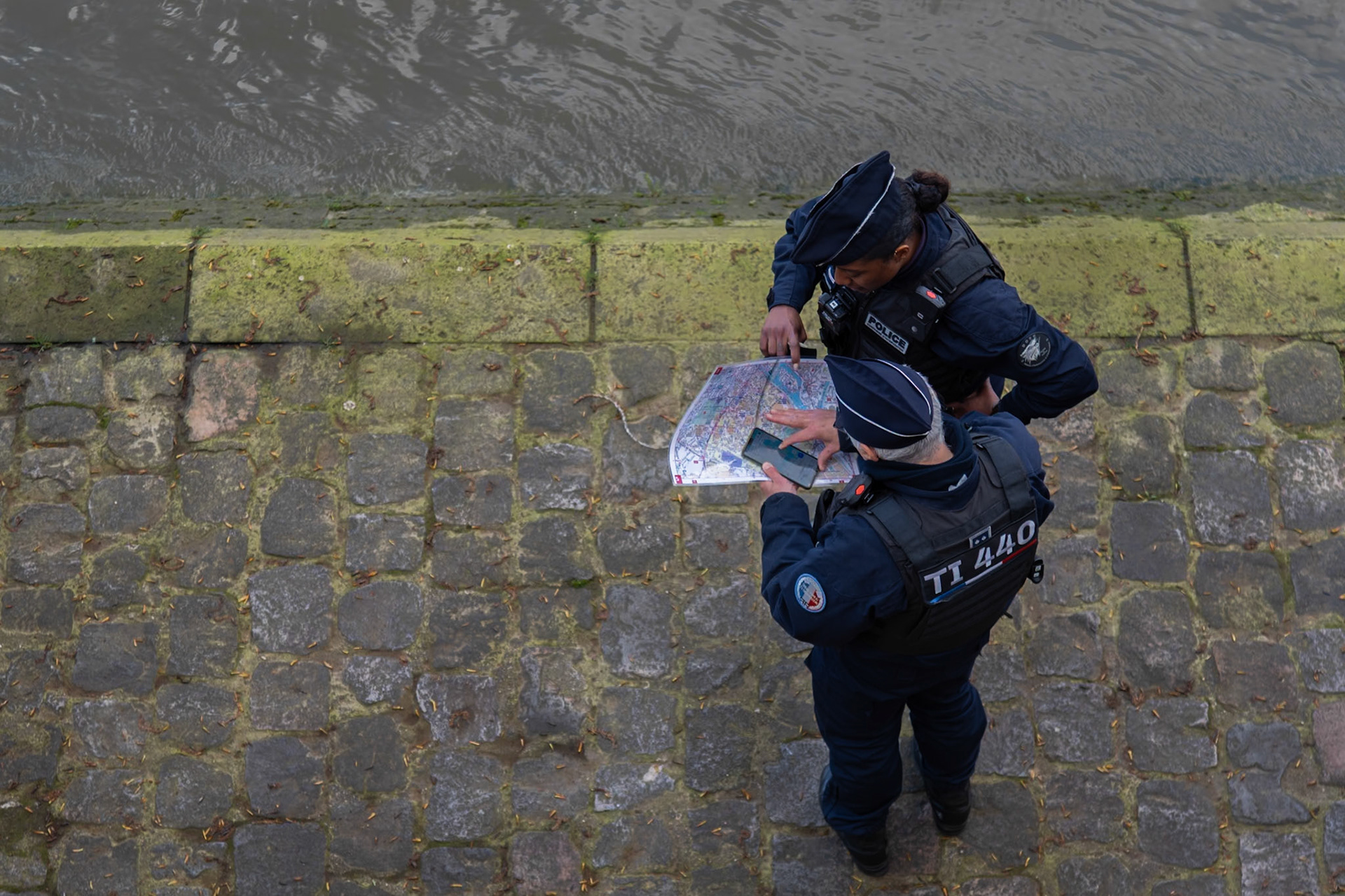 Two police officers have a look at a map at the beginning of a police operation on the banks of the Seine. Paris, April 3, 2024.