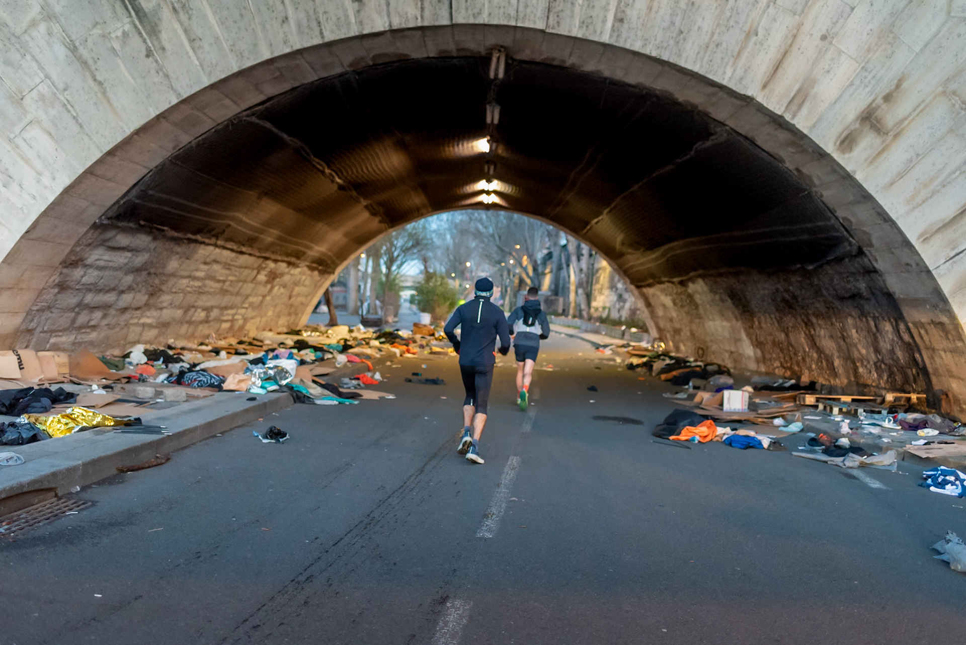 Joggers are running under the bridge ‘Pont Marie’ a day after a homeless encampment was cleared from the area. Paris, March 7, 2024.