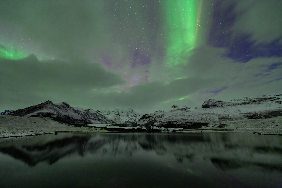 Glowing aurora over a lake near Skaftafell glacier, southern Iceland.