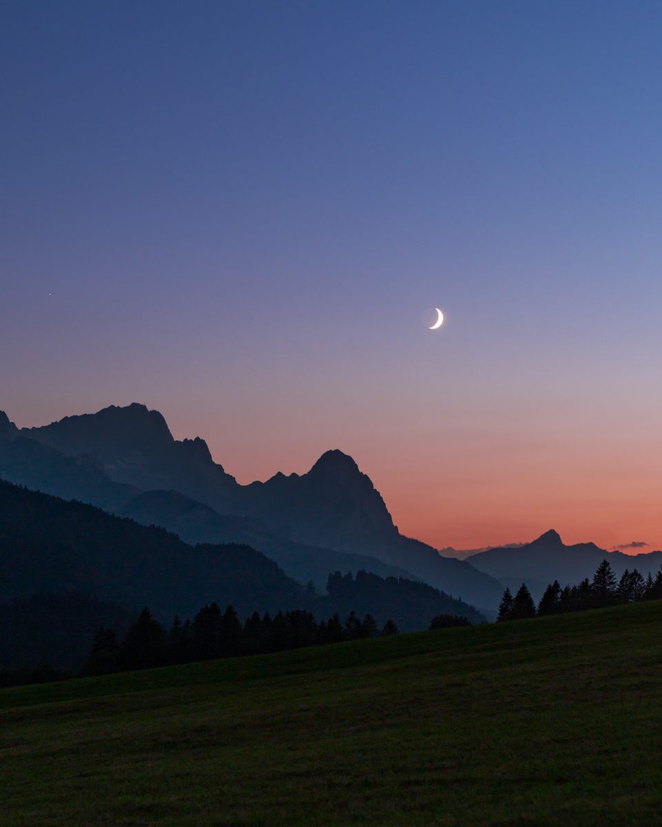 Crescent Moon over Bavarian Alps at Dusk.