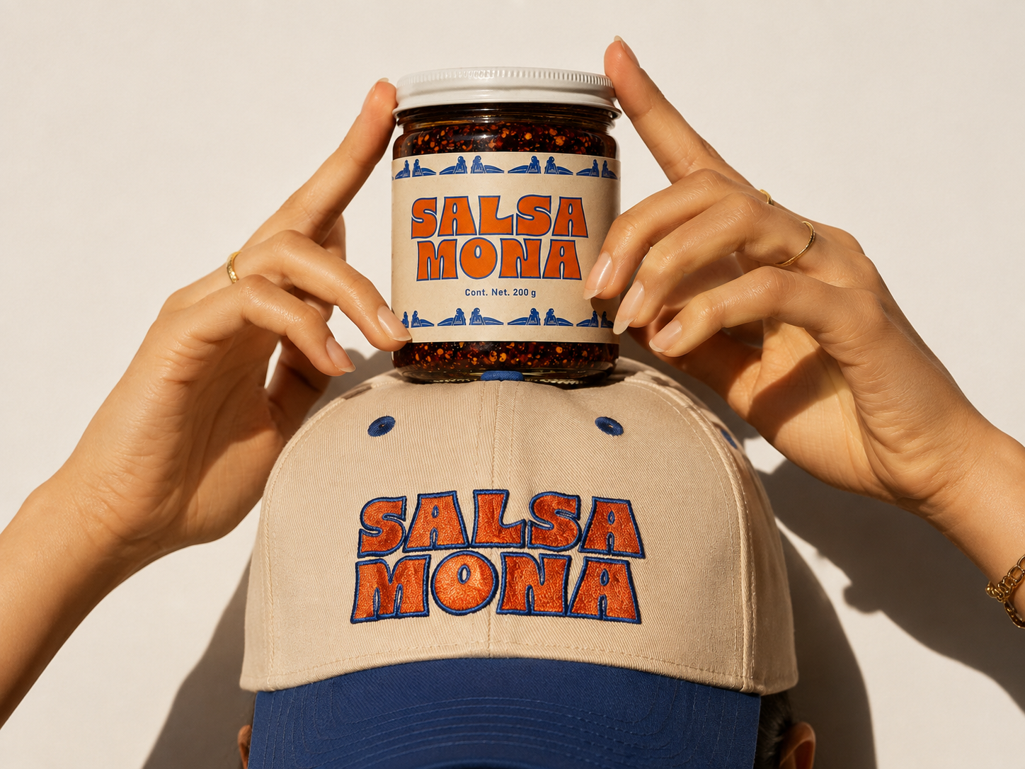 Salsa macha artesanal Salsa Mona en frasco de 200 g sobre una gorra bordada con el logotipo de la marca mexicana.