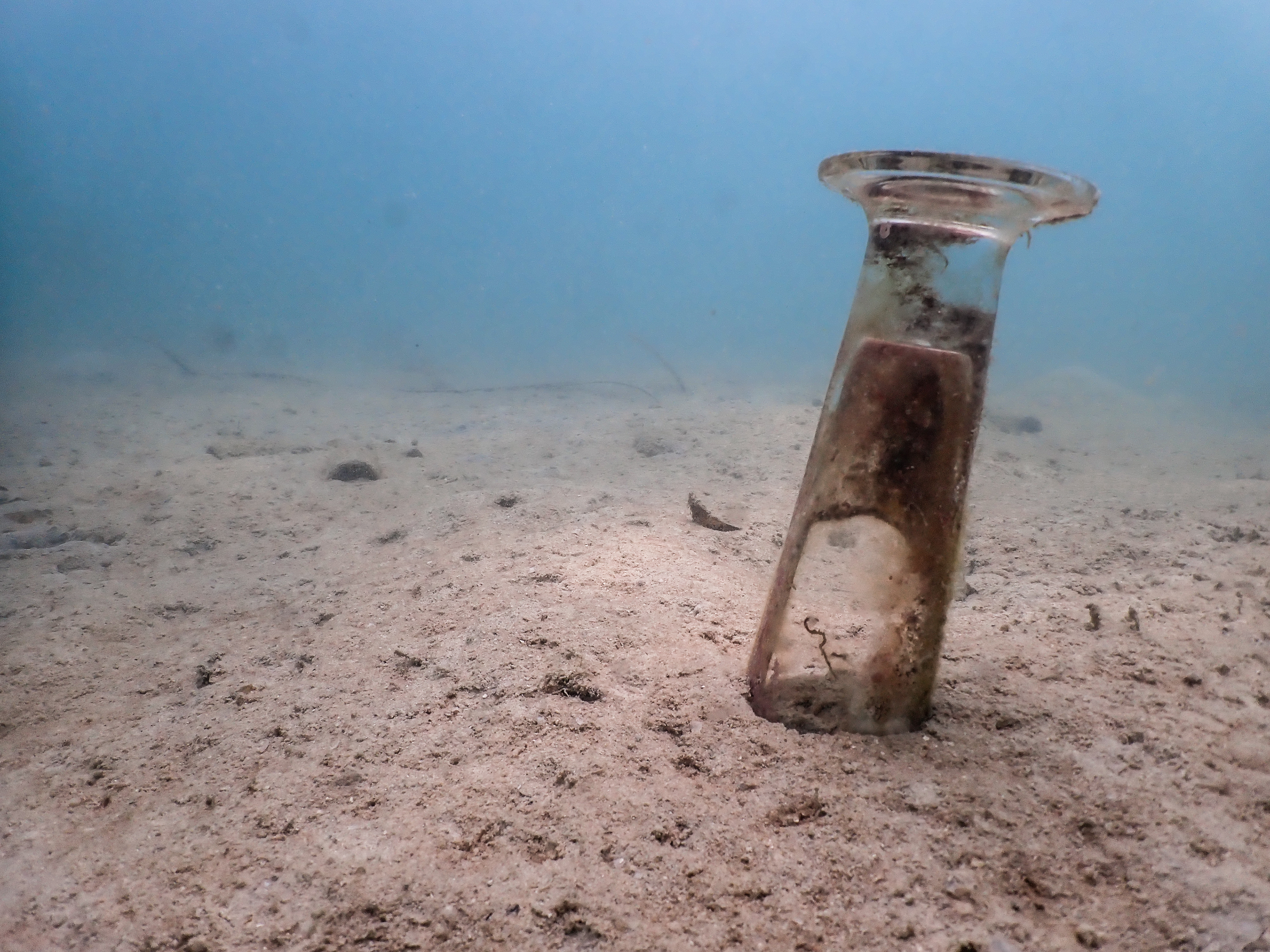 A glass in the sand on the ocean floor