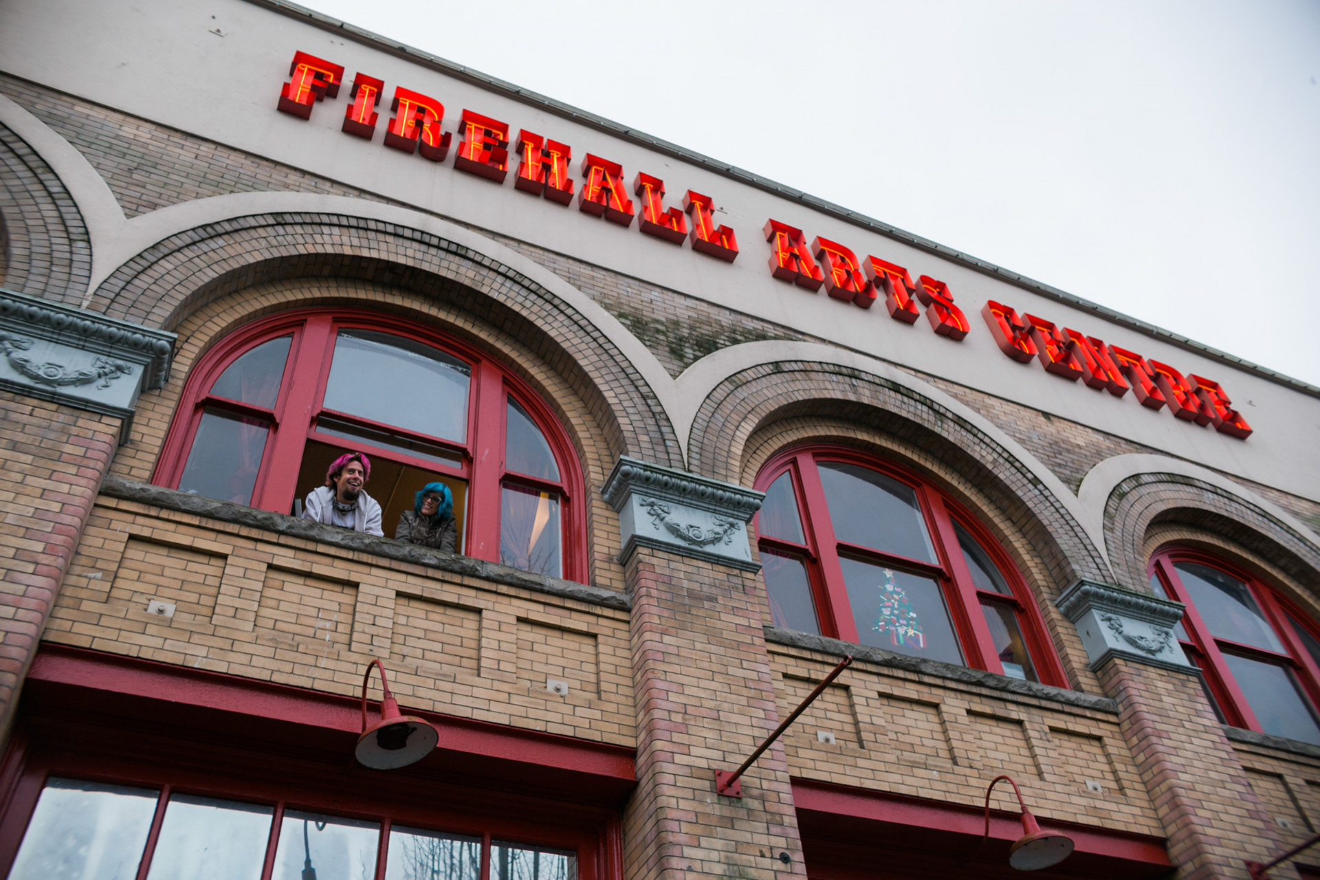Vancouver, B.C.—Mike Allen and Katheryn Petersen peak outside of the Firehall Arts Centre as part of a physically distanced performance during the pandemic. The pair perform under the name Teapot in the Tuba, a “miniature circus-jazz orchestra.” Photo by Kayla Isomura
