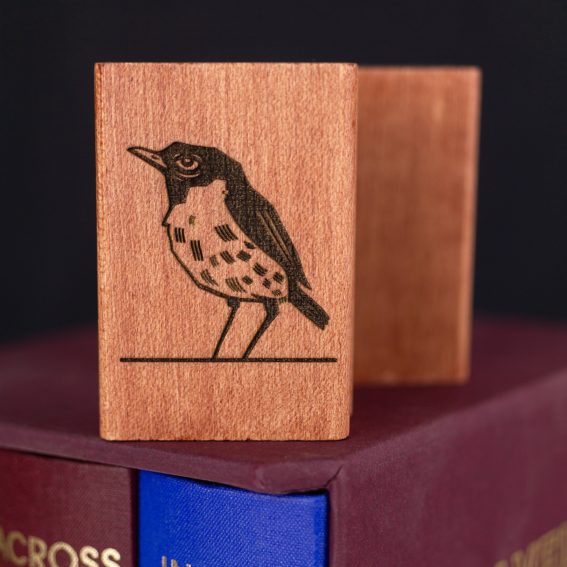 A rubber stamp with a bird illustration and the text “EX LIBRIS CLÉMENT SCARPI” lies next to its stamped impression on white paper.