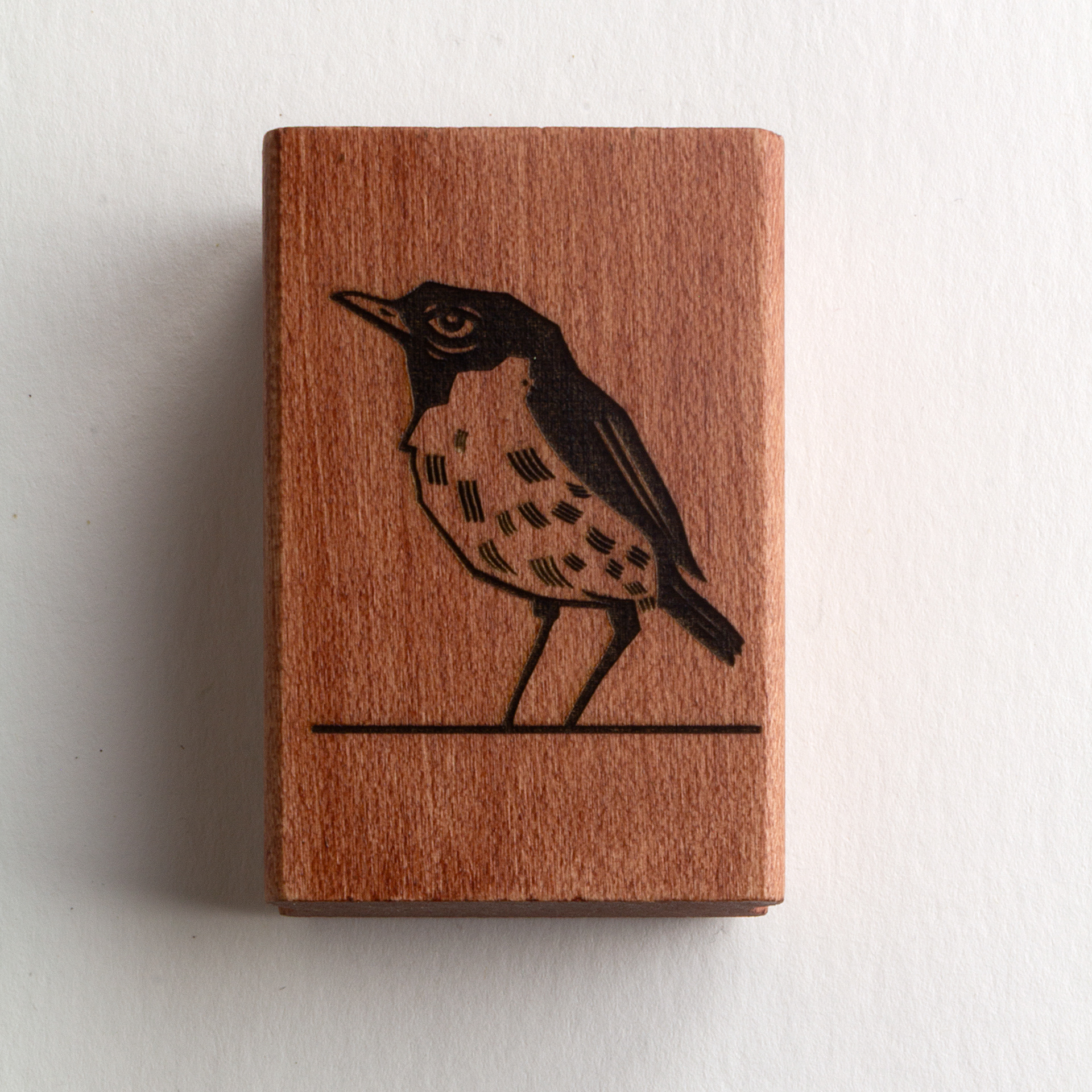 A rubber stamp with a bird illustration and the text “EX LIBRIS CLÉMENT SCARPI” lies next to its stamped impression on white paper.