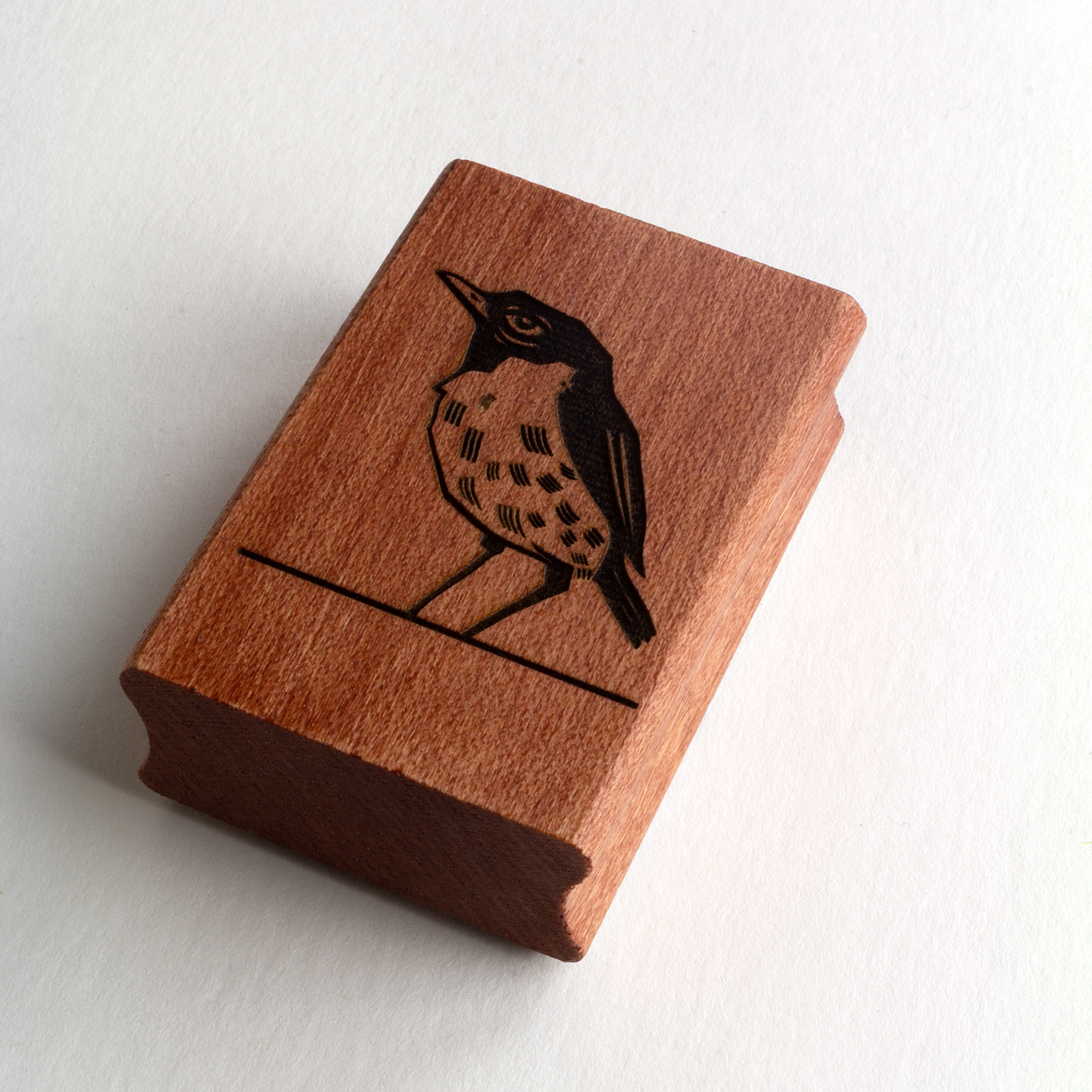 A rubber stamp with a bird illustration and the text “EX LIBRIS CLÉMENT SCARPI” lies next to its stamped impression on white paper.