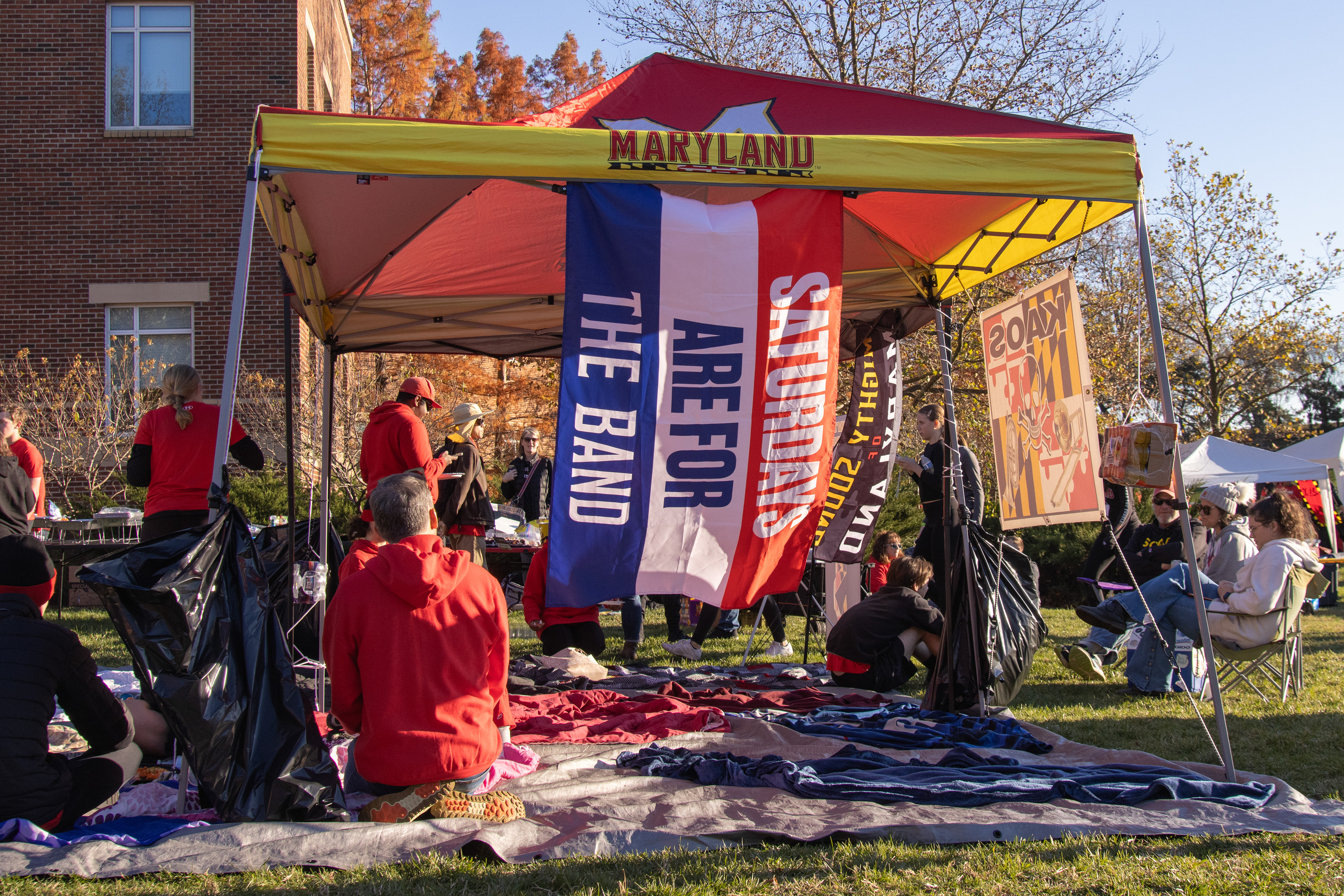 A "Saturdays are for the band" flag hangs from a tent at the Mighty Sound of Maryland's tailgate before the football game on the lawn of the Clarice Smith Performing Arts Center on Nov. 16, 2024. 